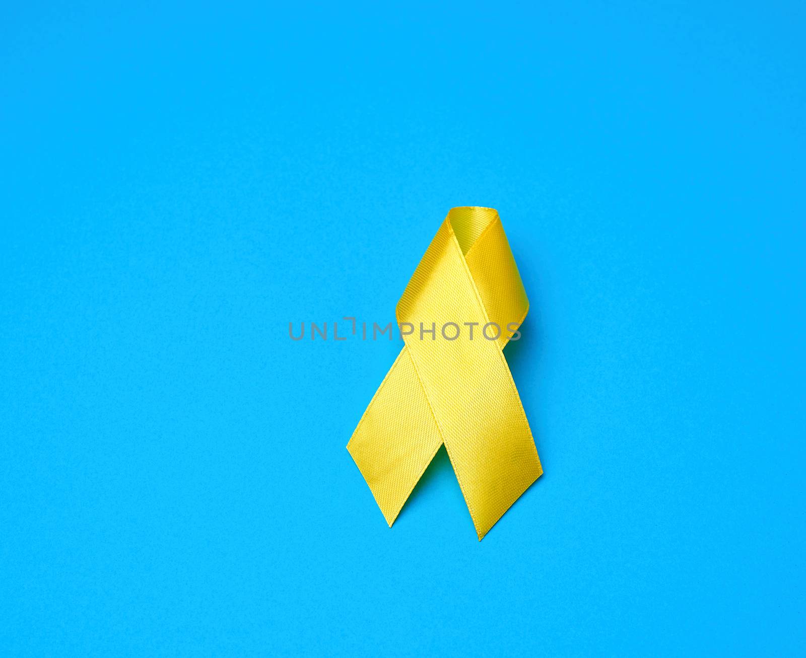 yellow ribbon on a blue background, symbol of the fight against the cat's tumor, problem of suicides and their prevention, close up