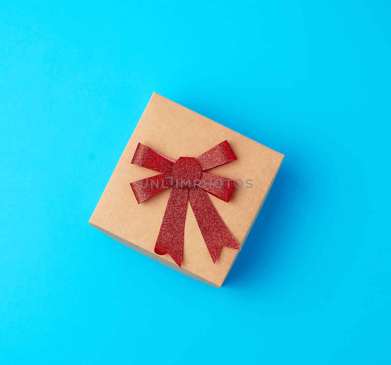 square gift box with a red bow on a blue background, top view, festive backdrop