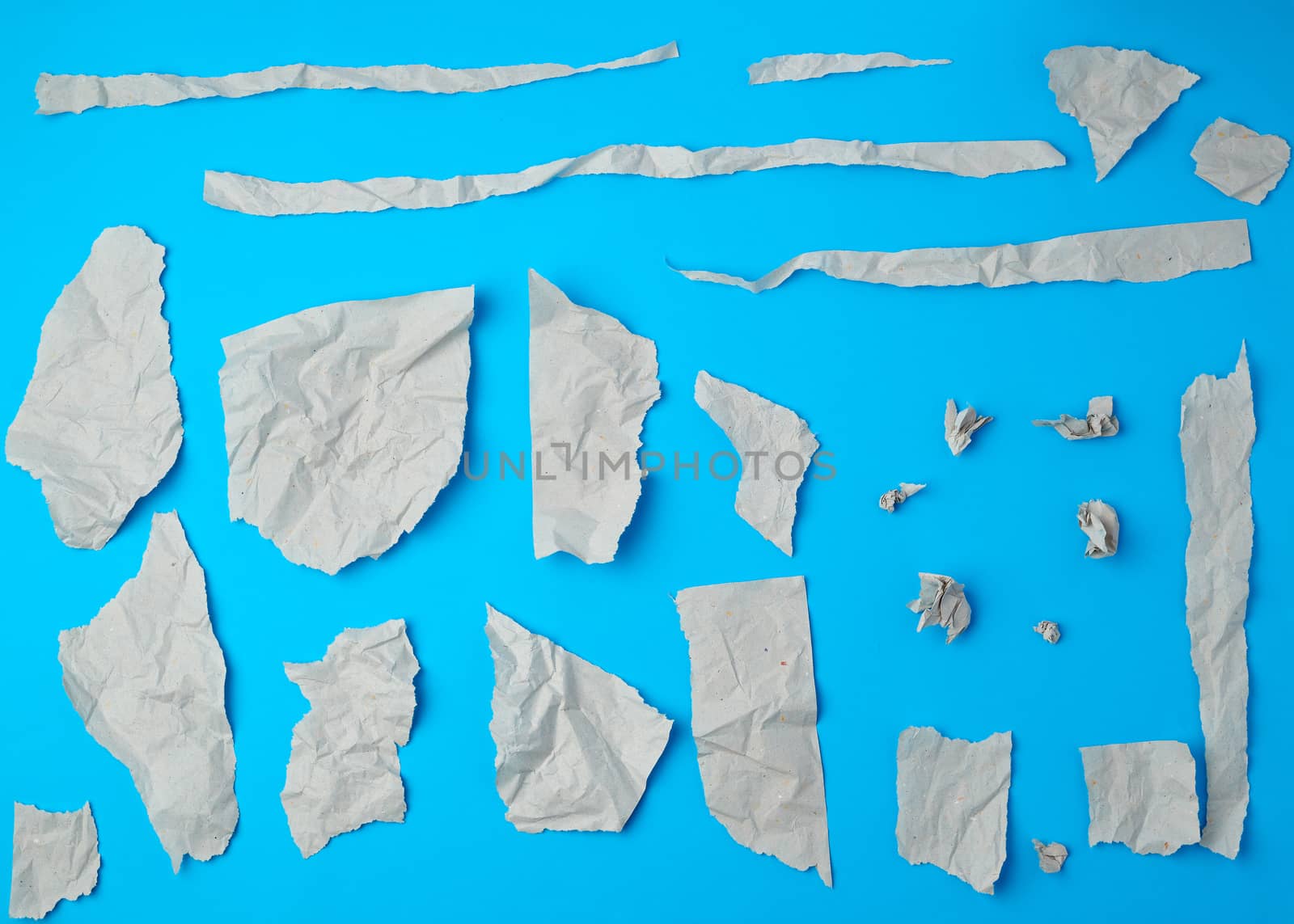 set of various pieces of torn gray crumpled paper on a blue background, close up