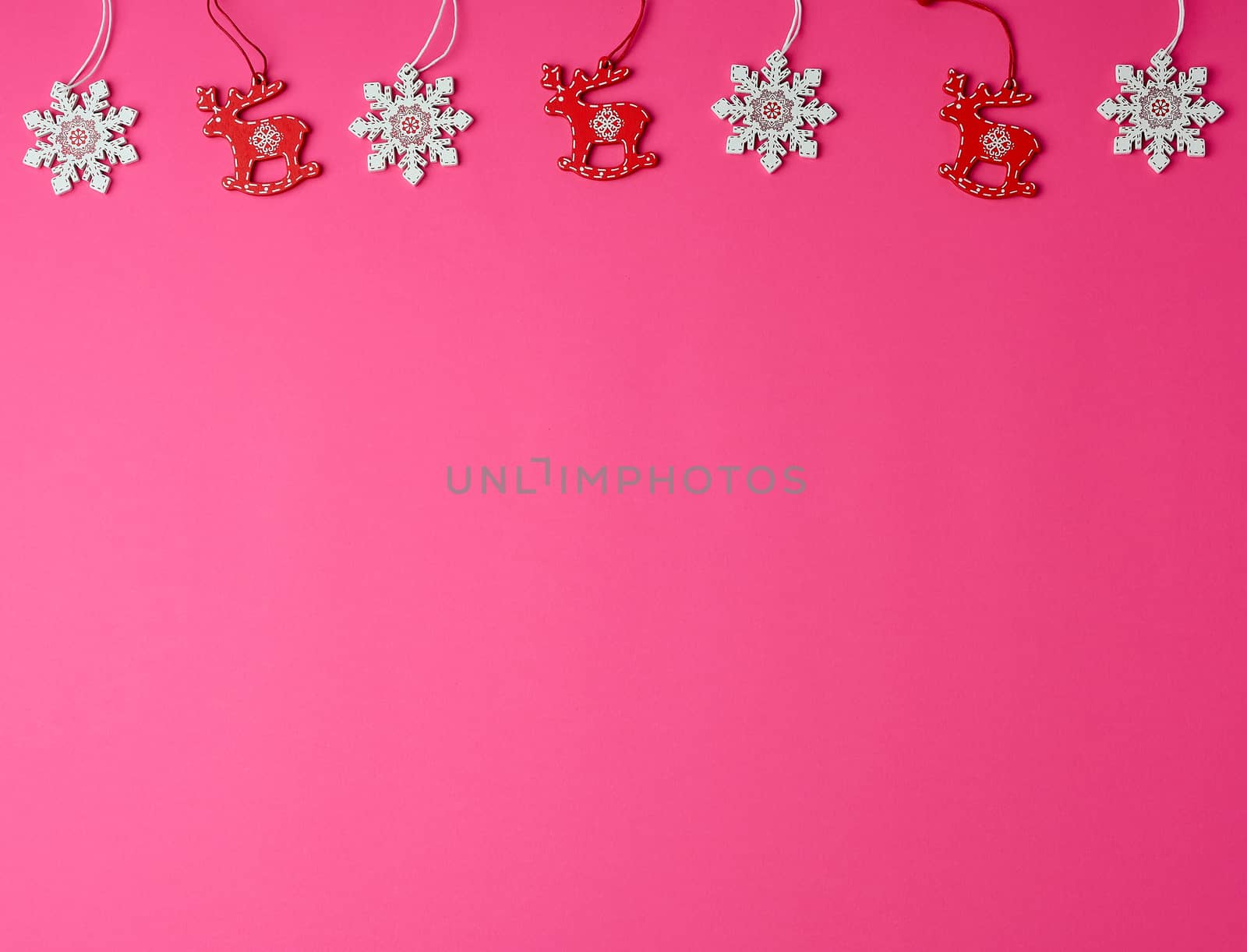 wooden carved Christmas decorations for the holiday tree on a pink background, copy space