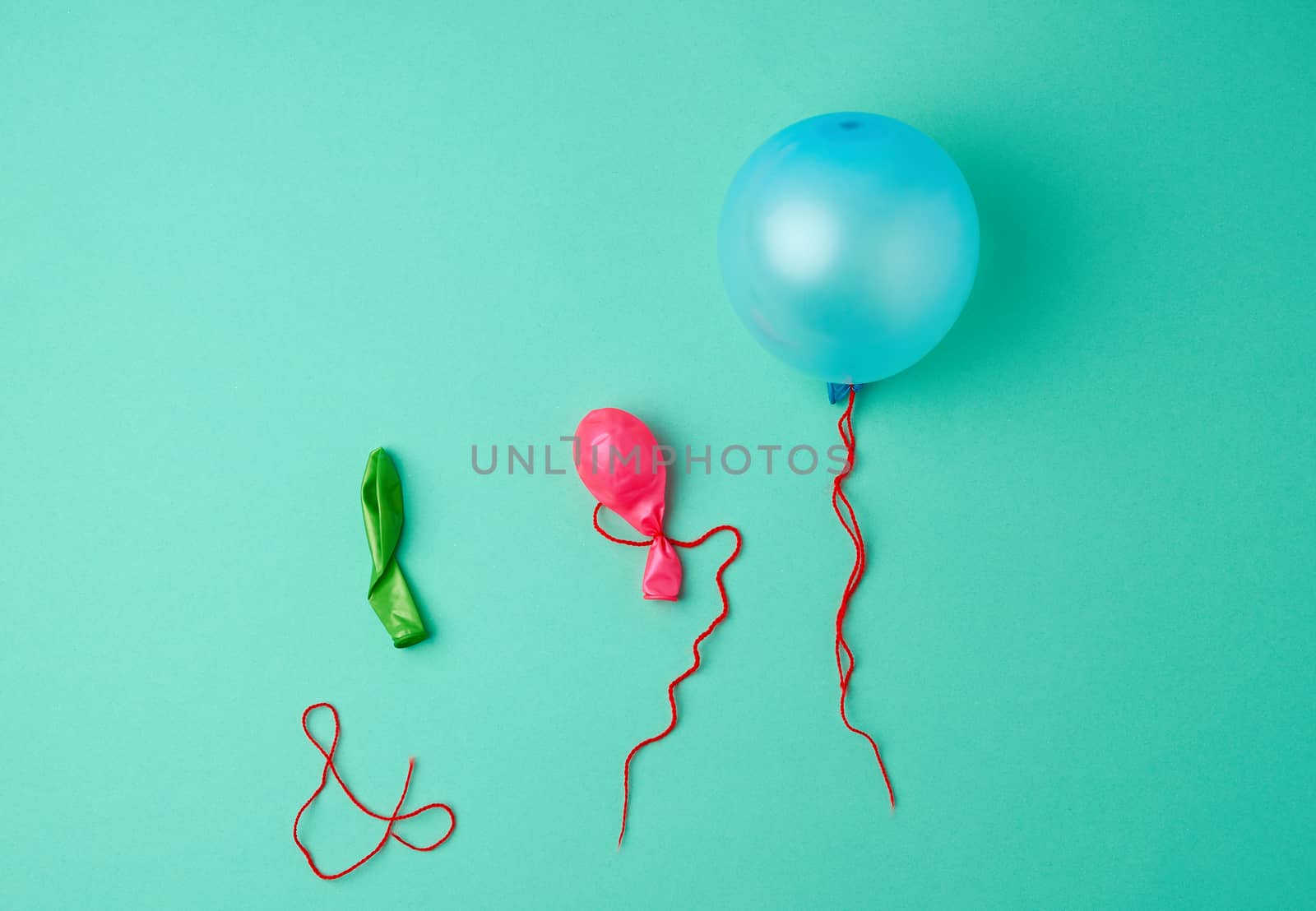 blue inflated and deflated rubber balls and red rope on a green background