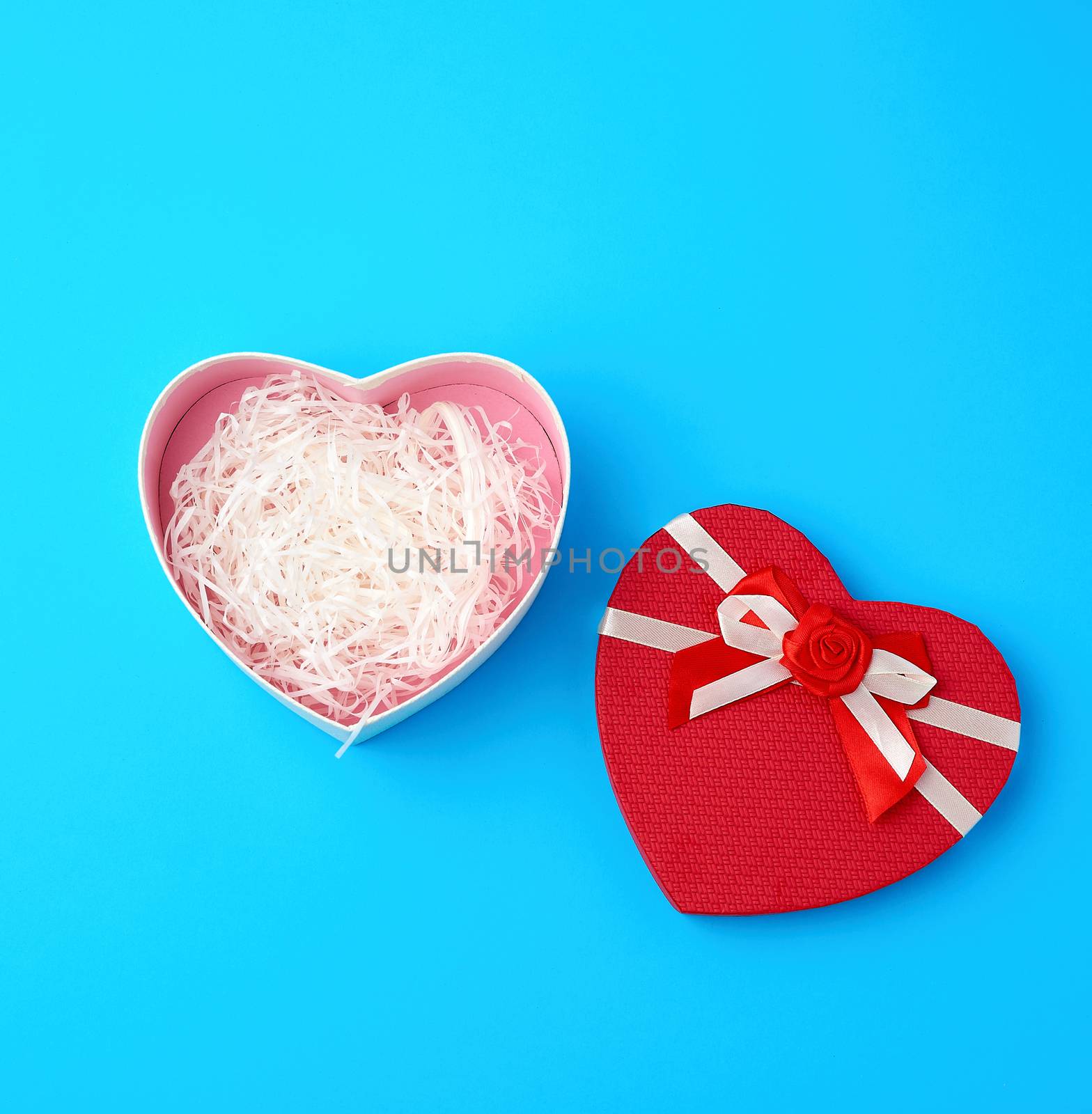 open red heart-shaped gift box with a bow on a blue background, top view, festive backdrop