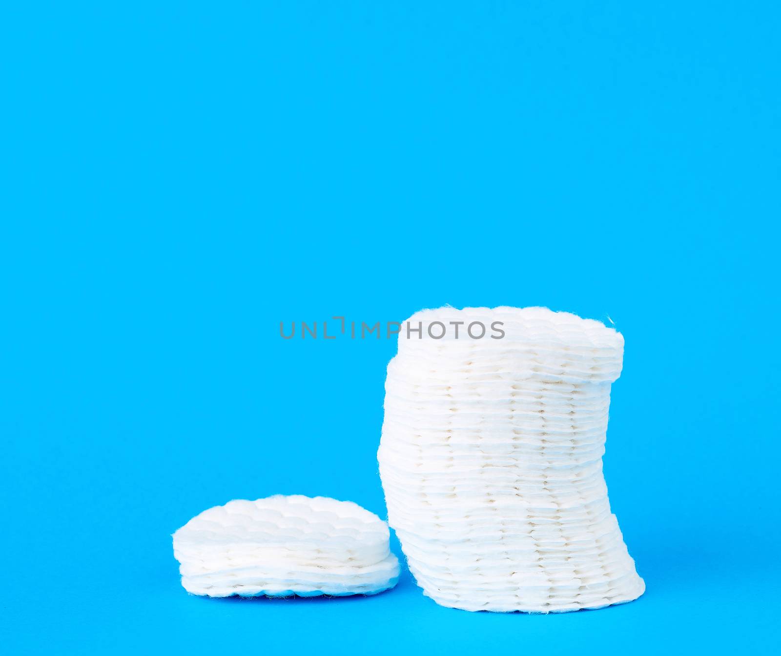 stack of white cotton round discs for cosmetic procedures on a blue background