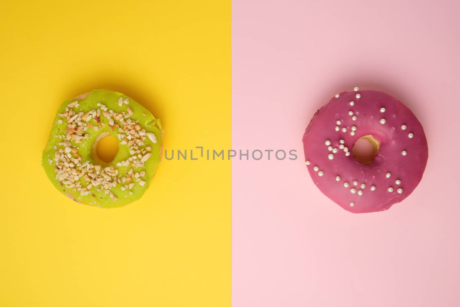 round different donuts with sprinkles on a bright multi-colored background, top view