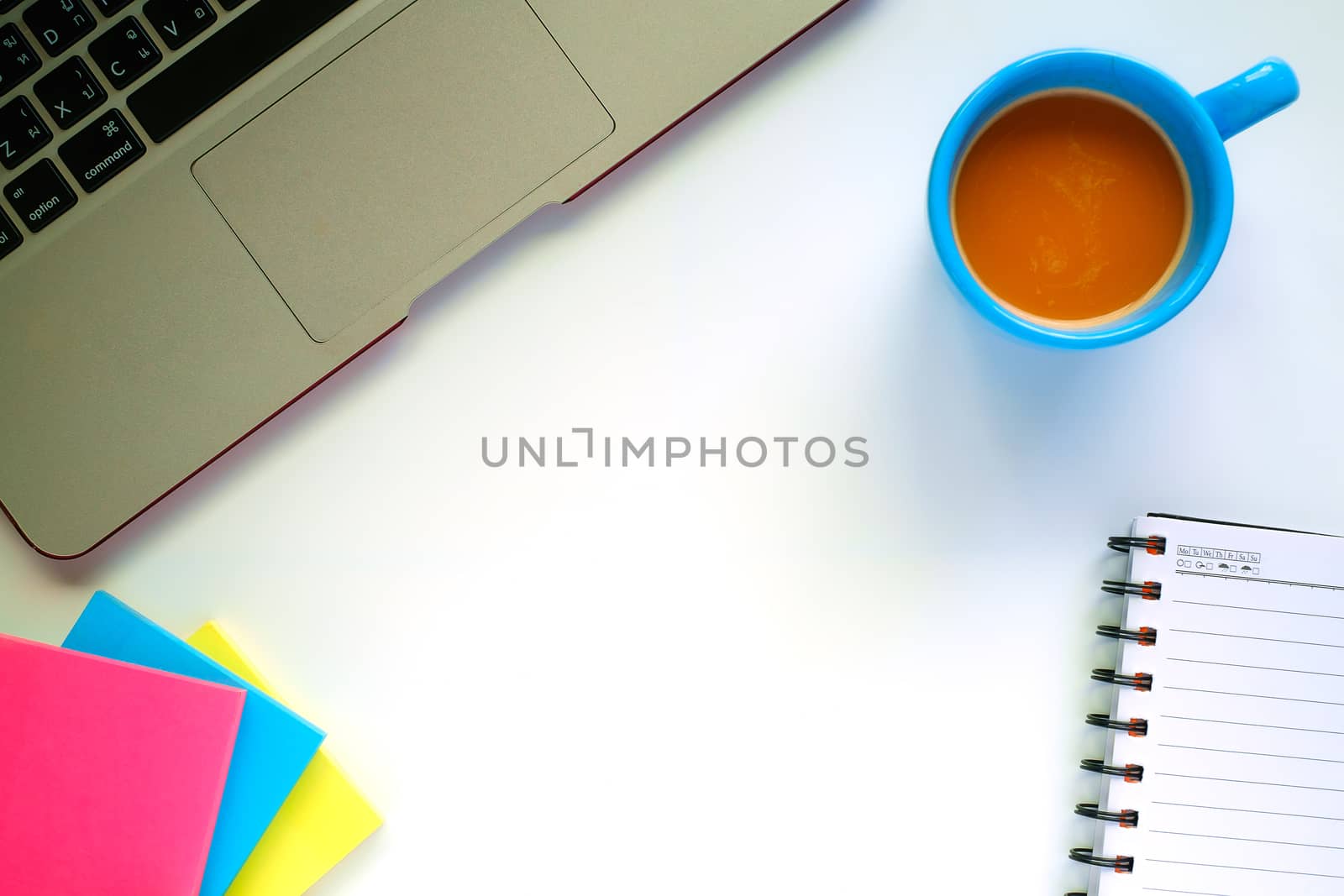 Top view of computer laptop, a cup of coffee and the other office accessories on the white table workplace