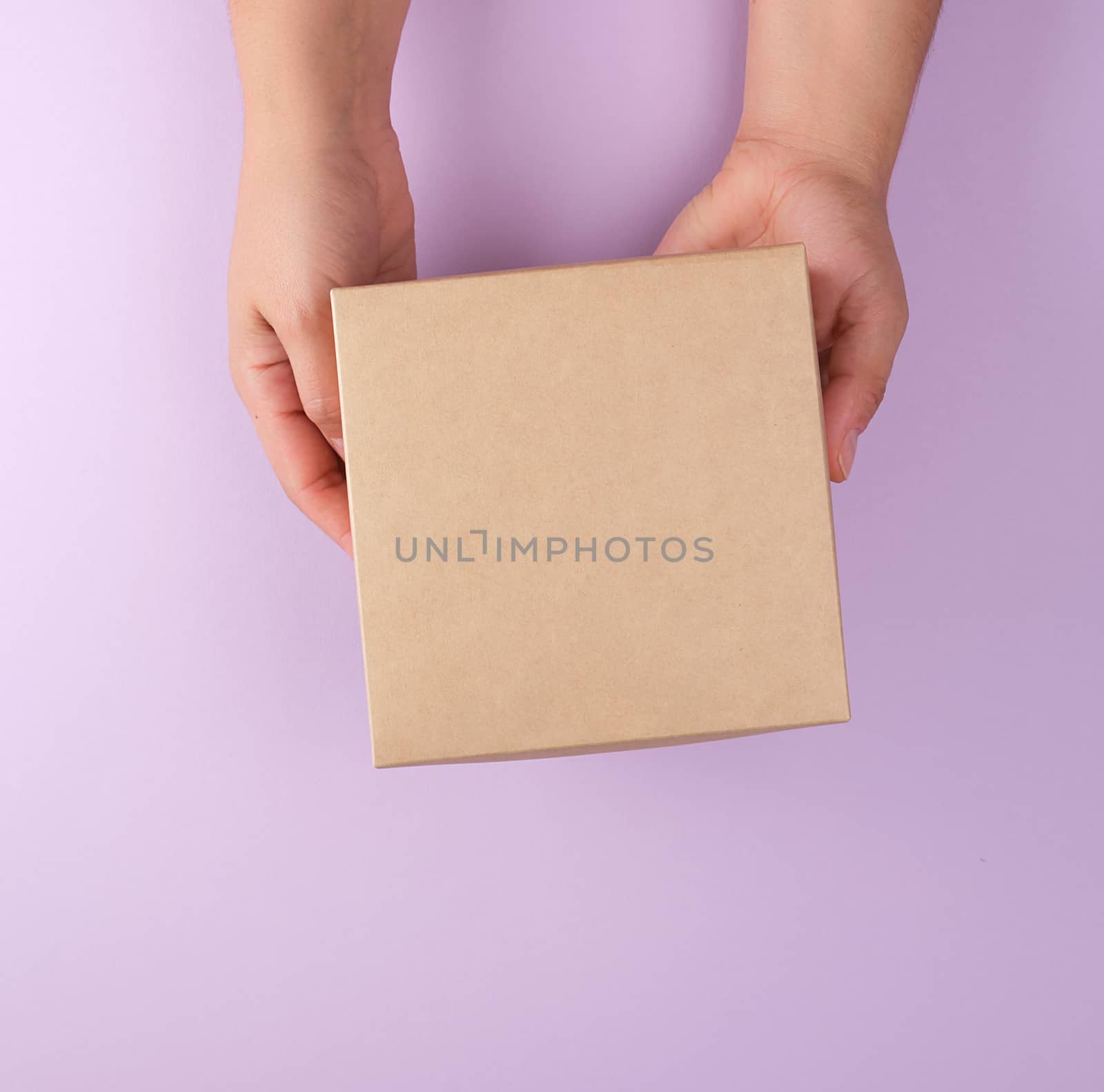 girl hold a brown square box on a purple background, top view, concept of giving gifts