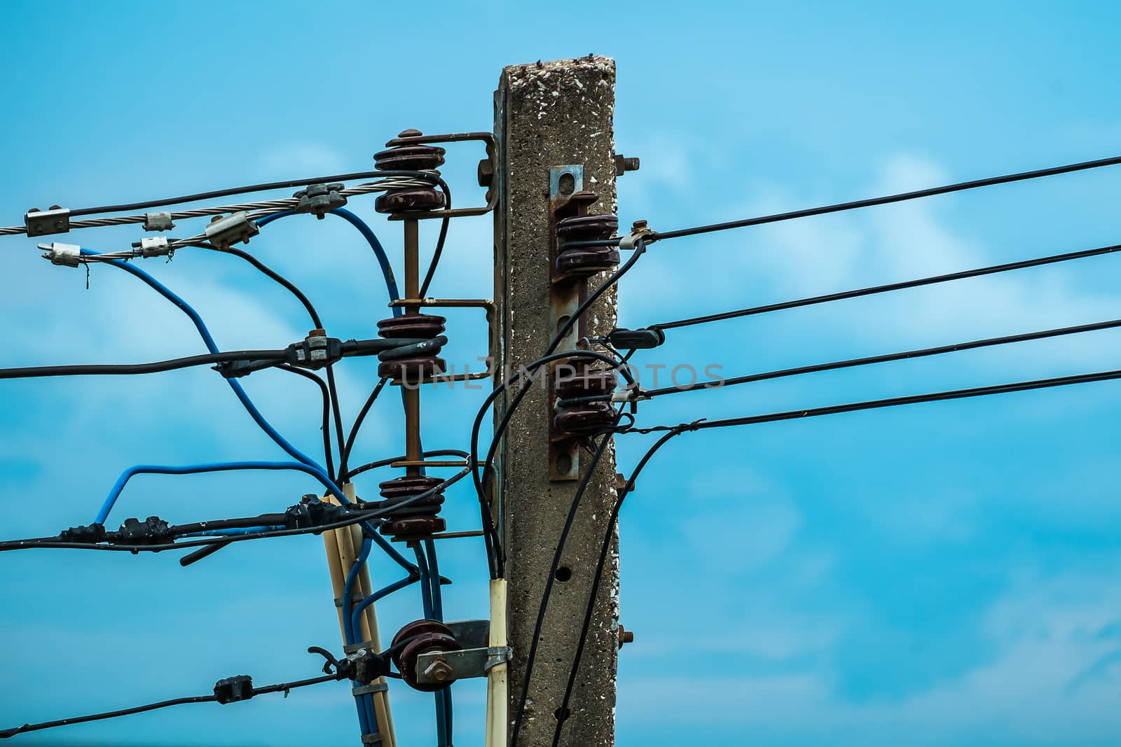 Electric pole with insulators and wires on blue sky