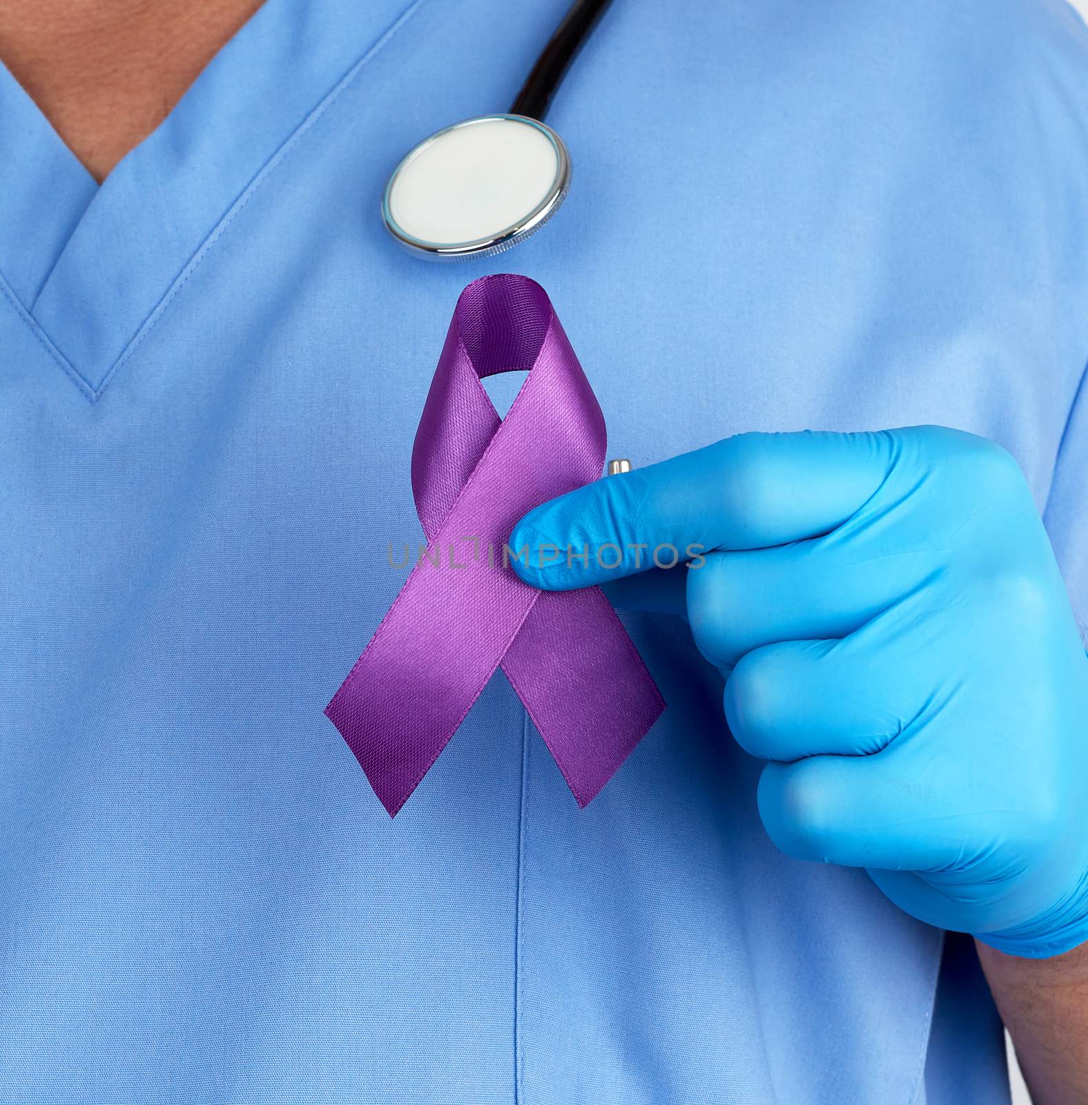 doctor in blue uniform and latex gloves holds a purple ribbon  by ndanko