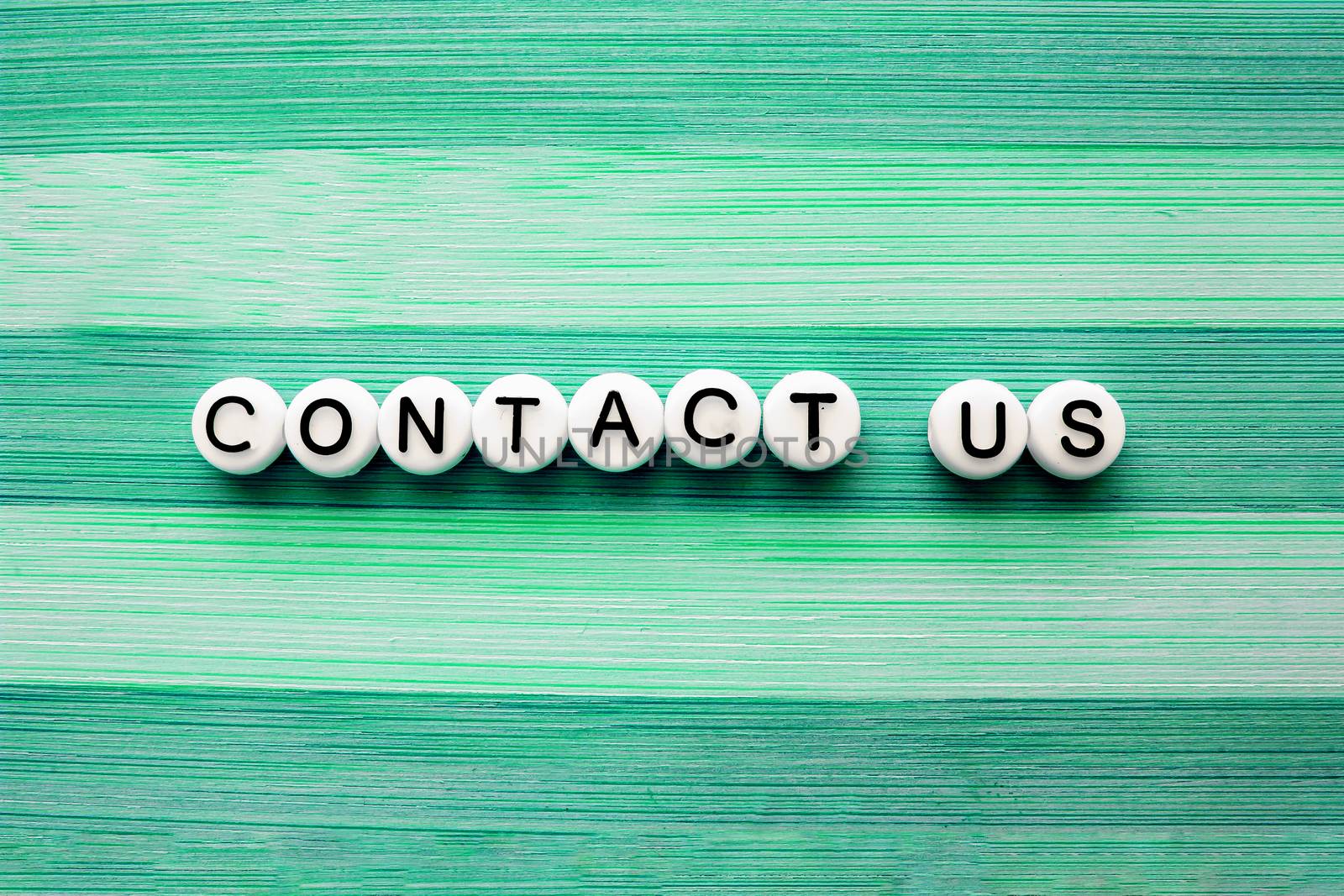 Contact us text on a green wooden table by oasisamuel