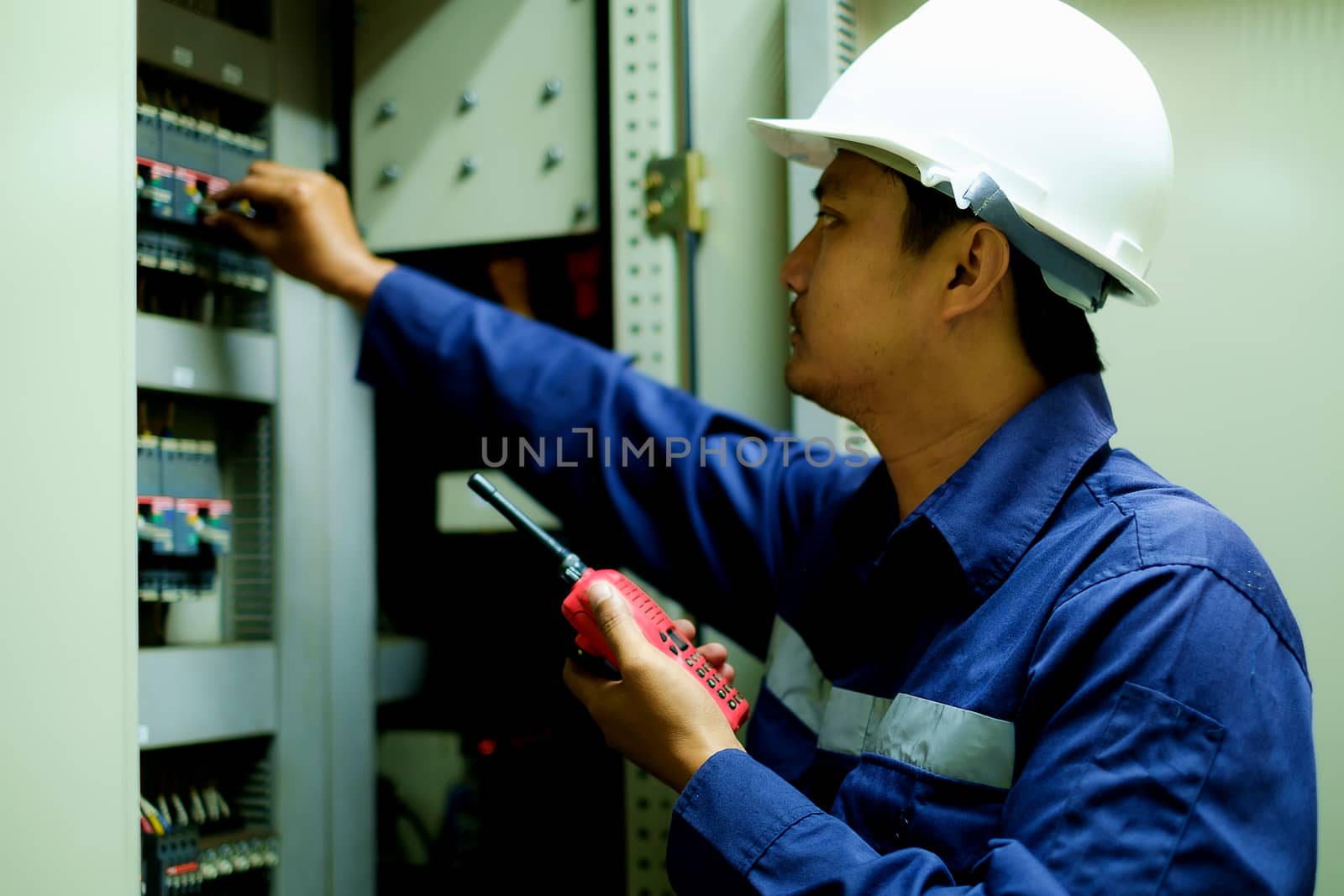 Engineer turning on switch in the electrical cabinet by iamnoonmai