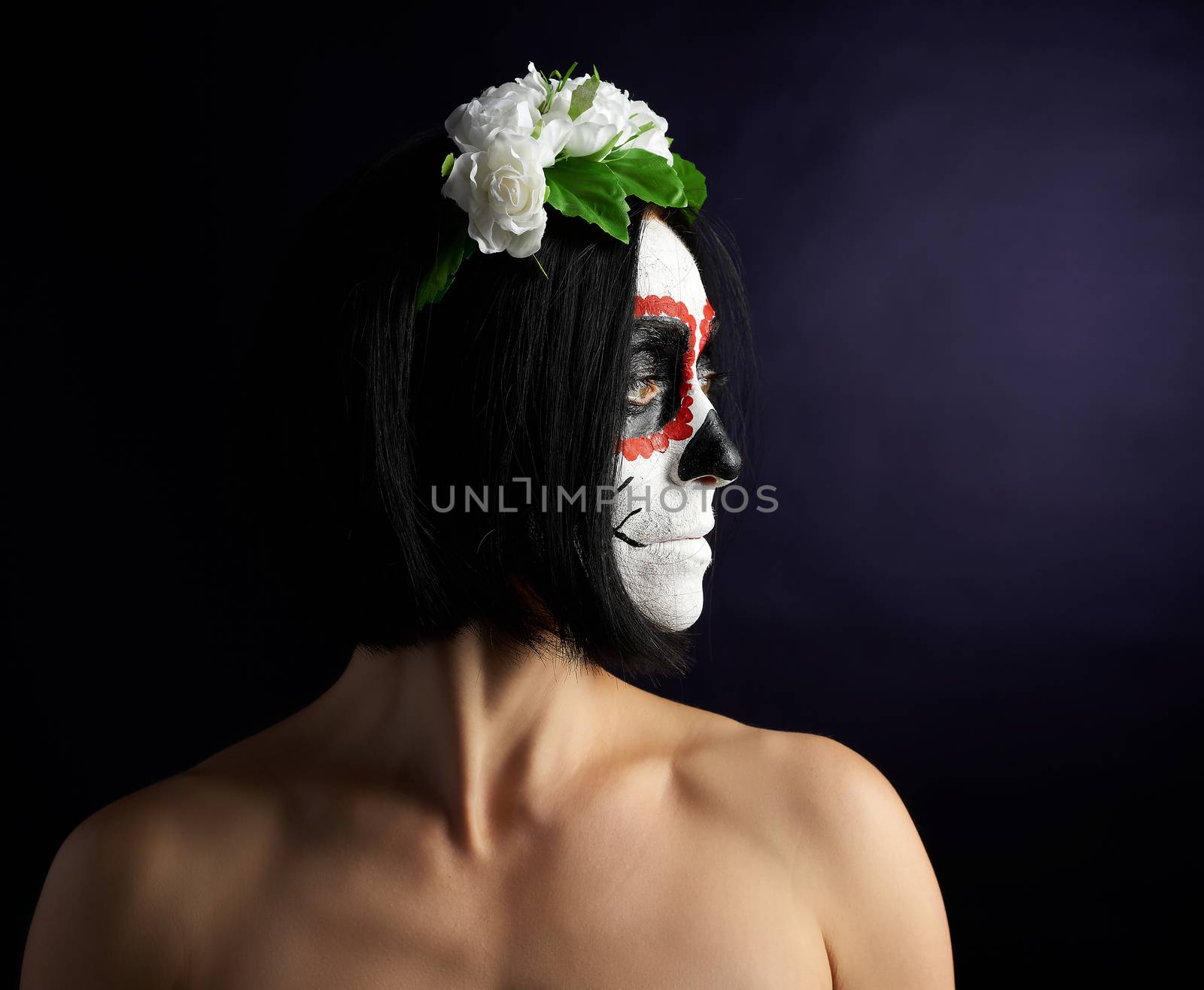 Young beautiful girl with traditional mexican death mask. Calavera Catrina. Sugar skull makeup. girl dressed in a wreath of white roses 