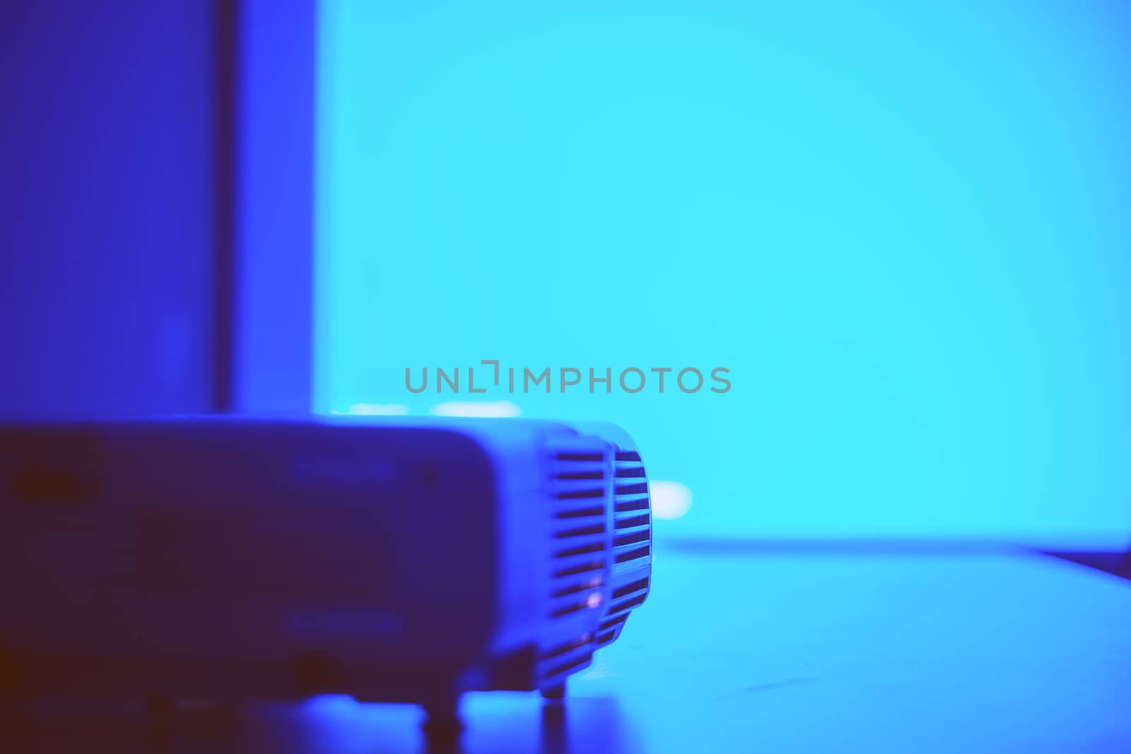 Screen with blue light from projector in the dark meeting room