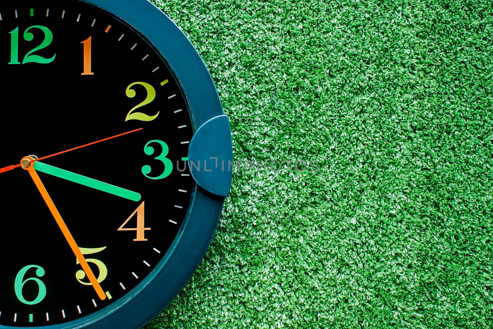 Clock on the plastic artificial green grass