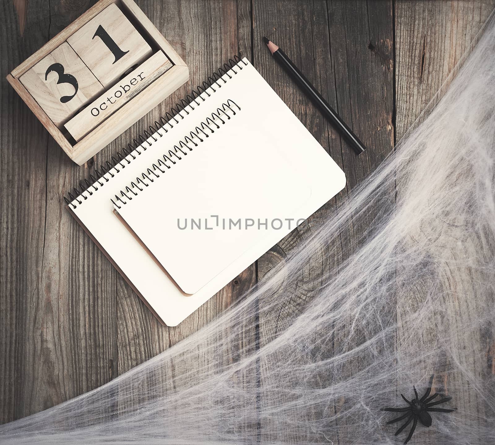 black spider figurines and wooden retro clock made of blocks with the date of October 31 on a gray wooden background, Halloween holiday