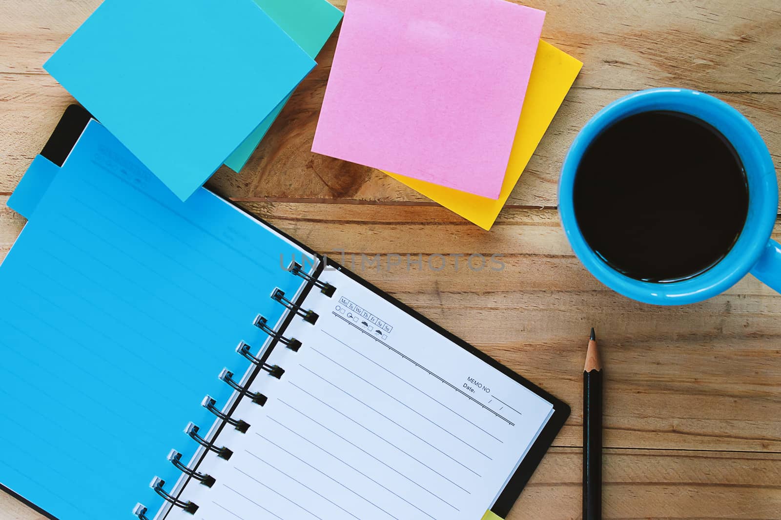 Top view of notebook, a cup of coffee, pencil and note pad on the wooden table, space for thinking and writing with the drinking time