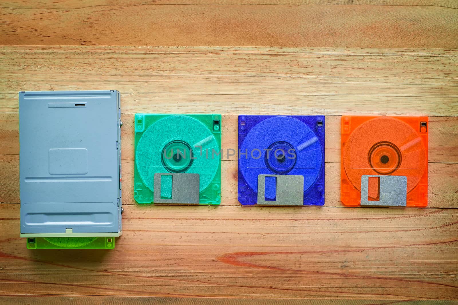 Floppy disk drive and diskettes on wooden table, old technology and legacy industrial computer equipment