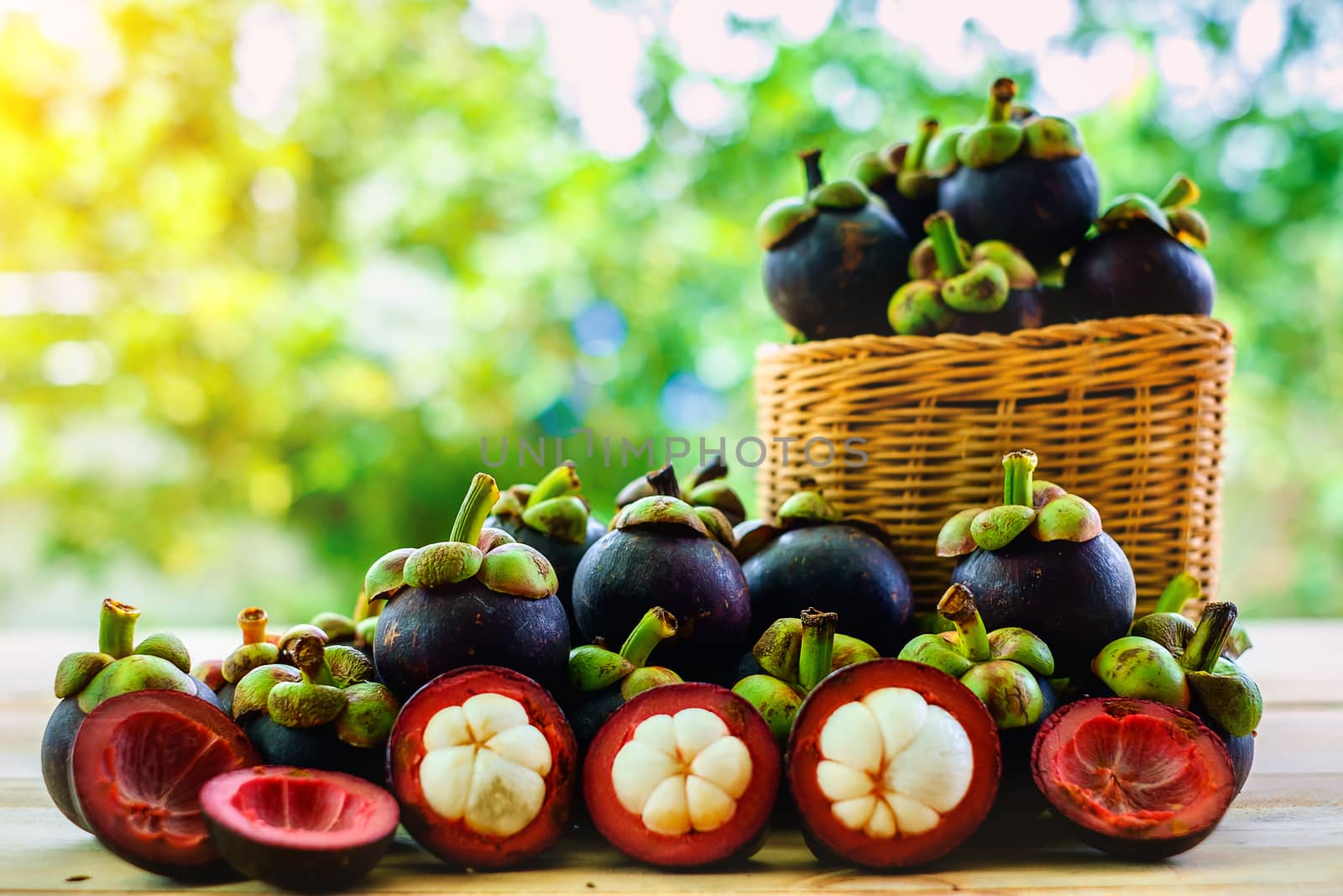 Mangosteen fruit in the basket on wooden table with blurred green background