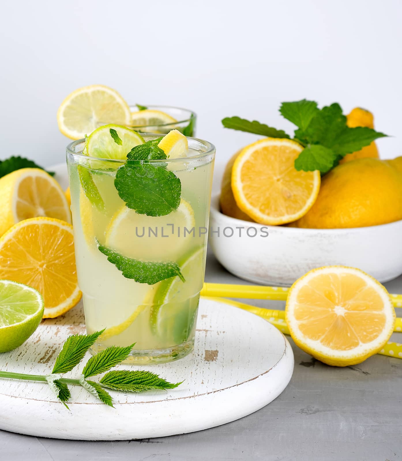 summer refreshing drink lemonade with lemons, mint leaves, lime in a glass, next to the ingredients for making a cocktail