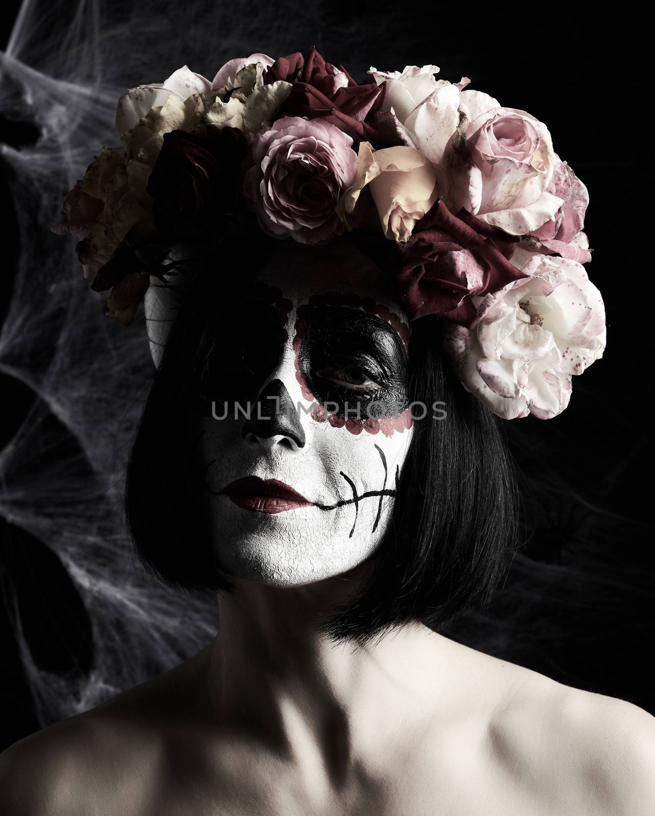 beautiful girl with traditional mexican death mask. Calavera Catrina. Sugar skull makeup. girl dressed in a wreath of roses on a background of white web