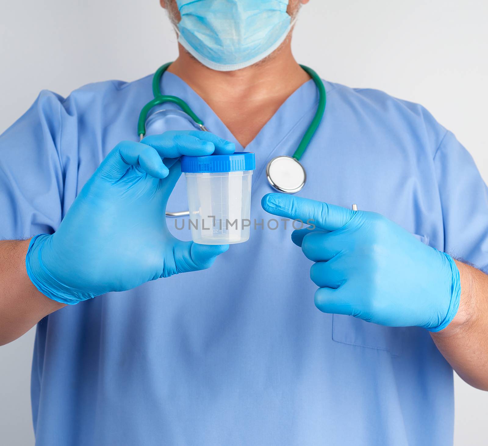 doctor in blue uniform and latex gloves is holding an empty plastic container for taking urine samples, close up