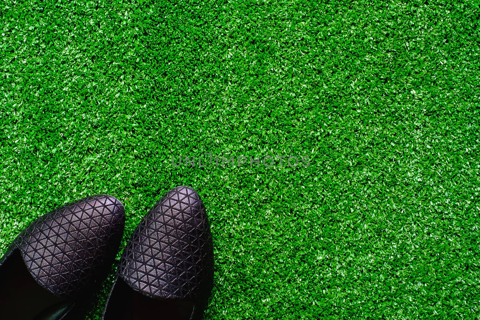 Black shoes on the plastic artificial green grass