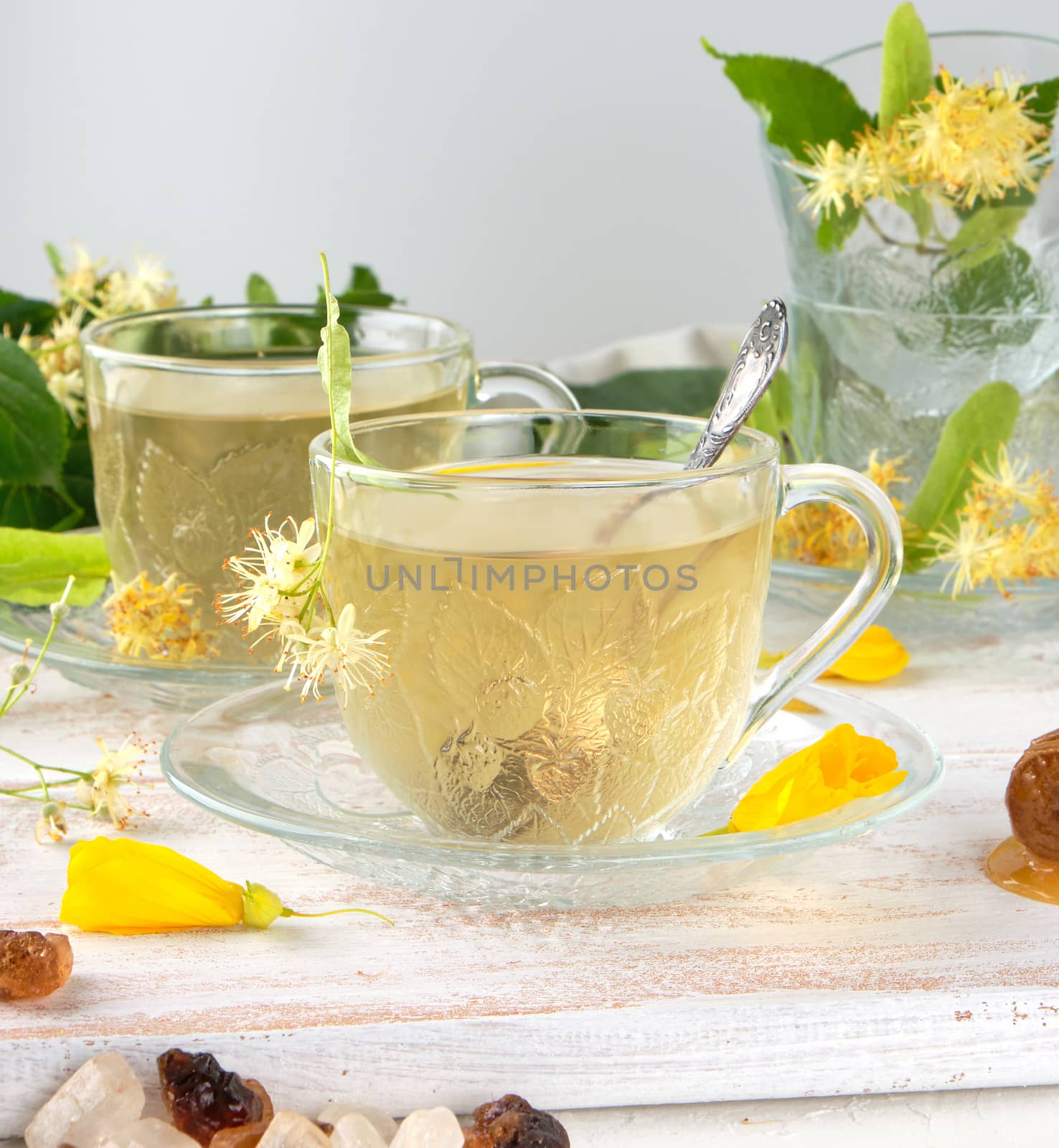 transparent cup with tea from linden on a white wooden board, close up