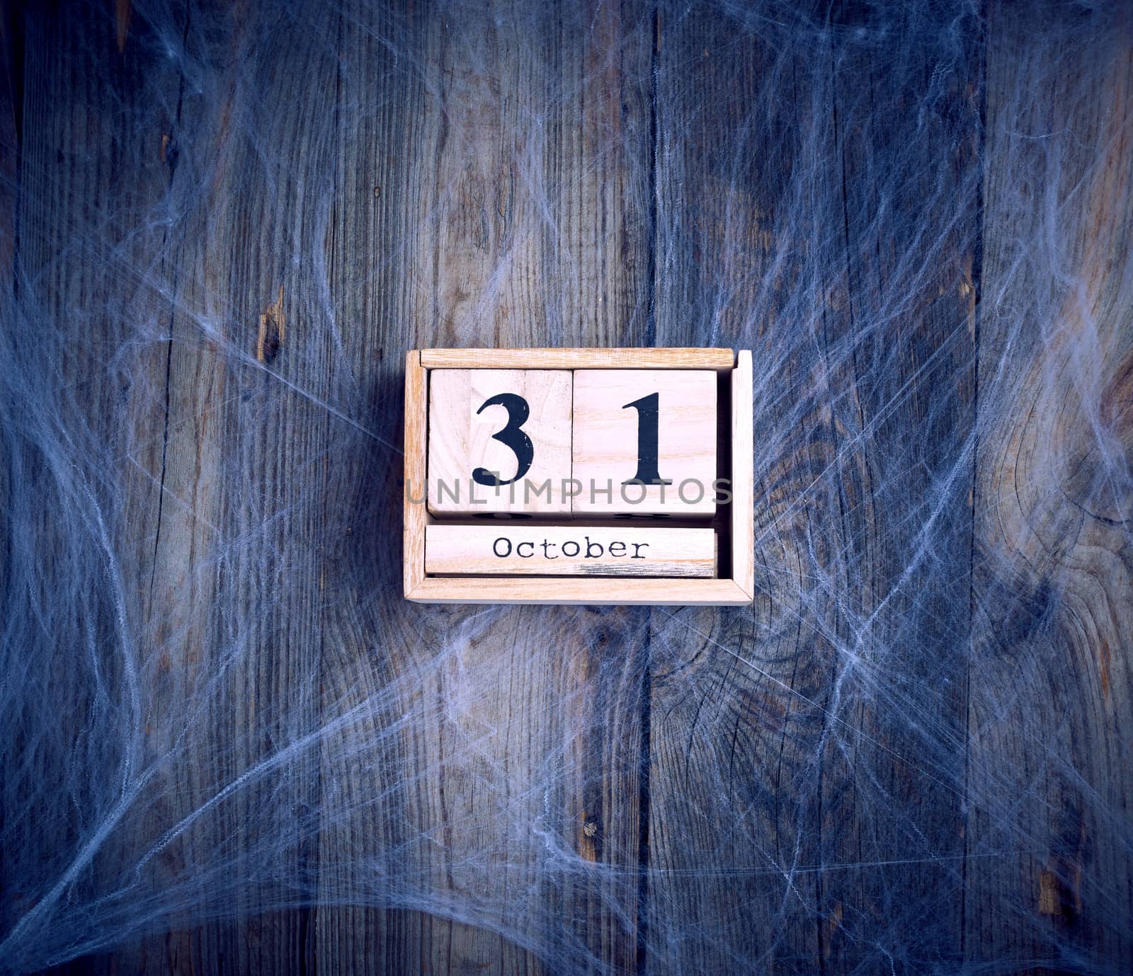 White spider web and wooden retro calendar made of blocks with the date of October 31, backdrop for Halloween holiday