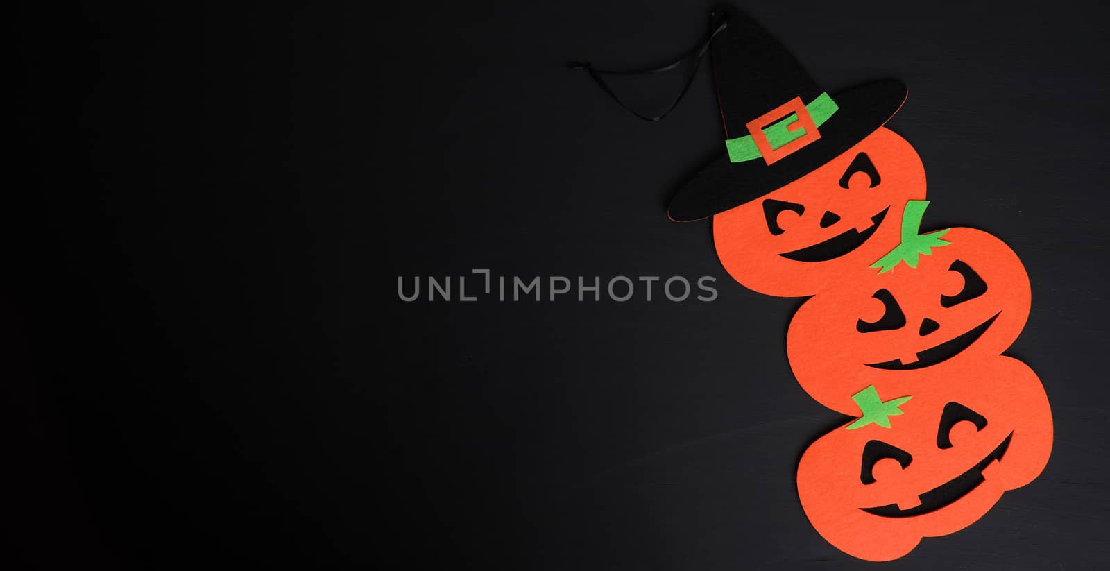 orange pumpkin felt figures on a black background, Halloween festive backdrop