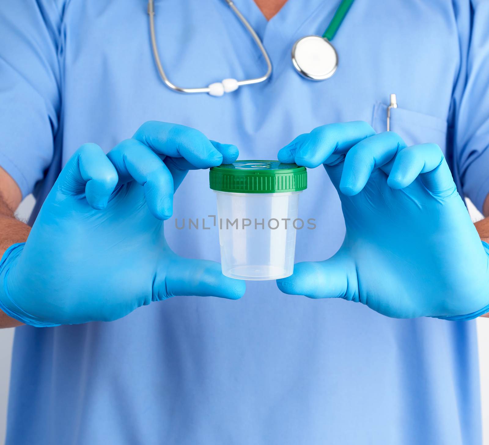 doctor in blue uniform and latex gloves is holding an empty plastic container for taking urine samples, concept of timely diagnosis