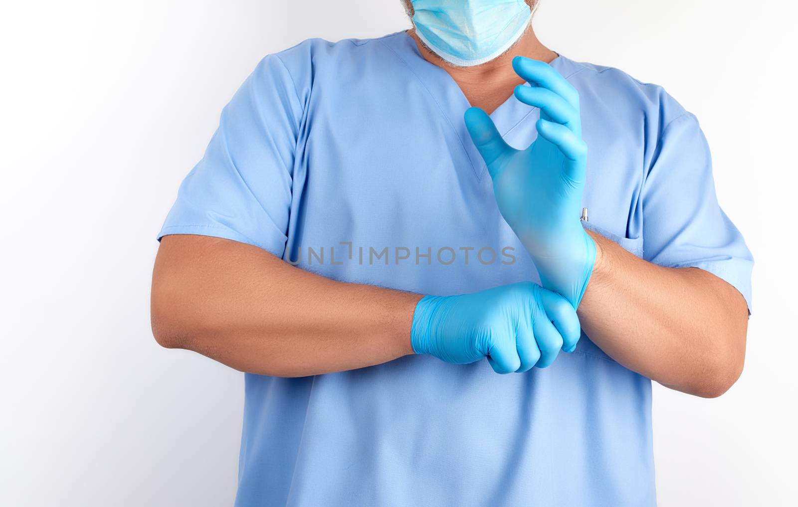 male doctor in blue uniform puts on his hands white sterile latex gloves before surgery, white background