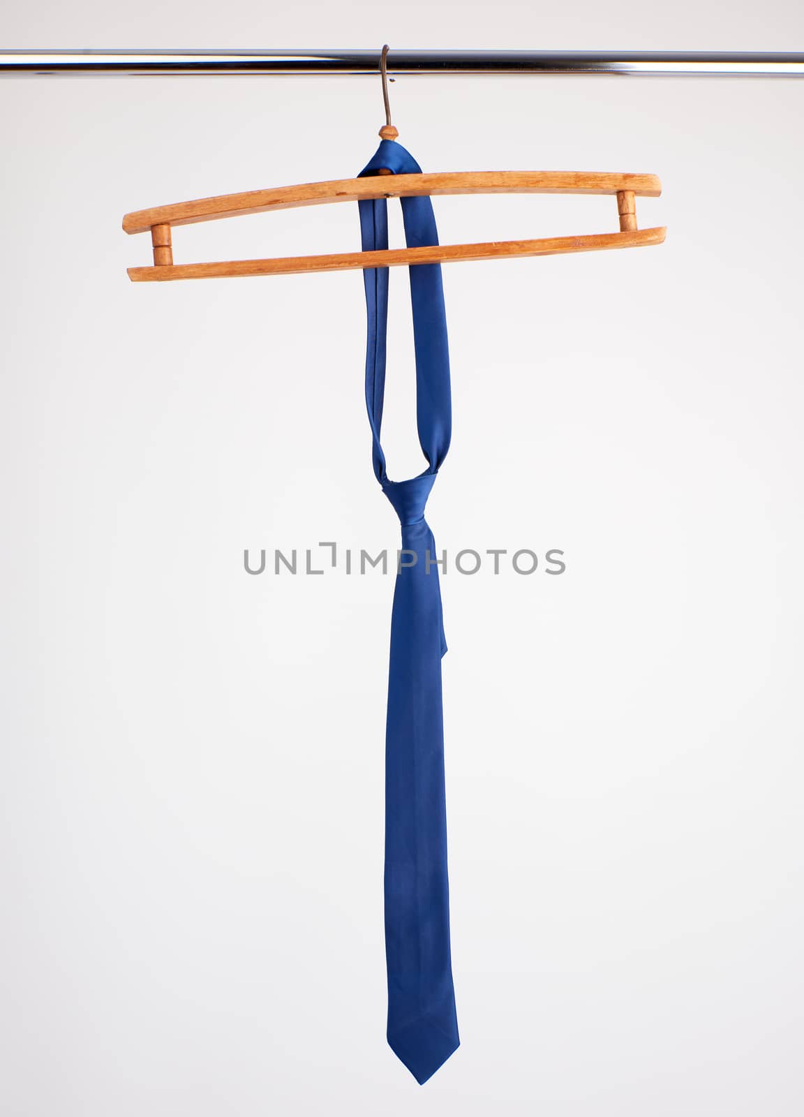 blue tie hanging on a wooden hanger, white background