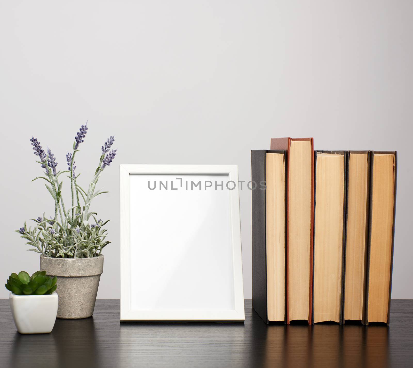 empty white photo frame, stack of books and a pot of growing lavender on a black table, workplace 