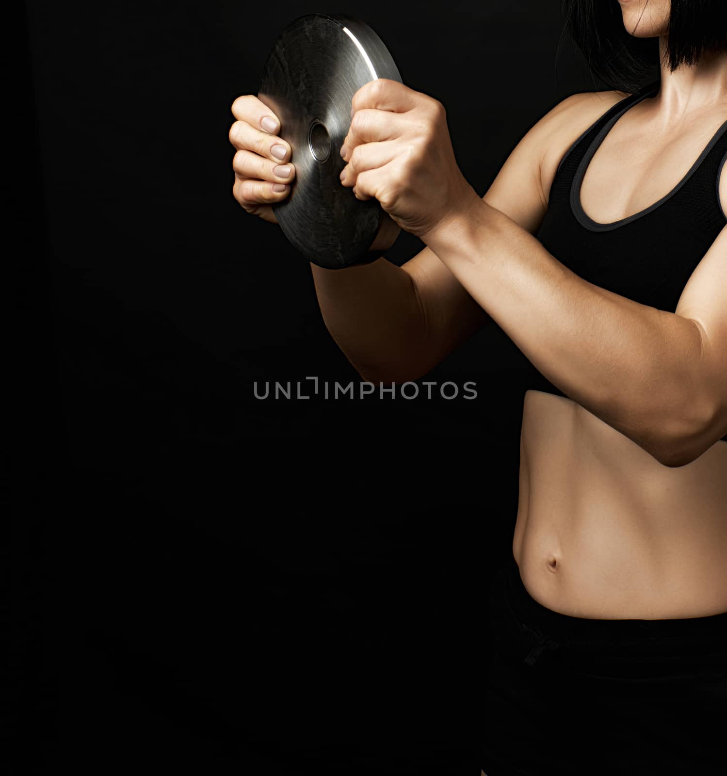 young woman with black hair and a sports figure holds a steel circle for sports, low key