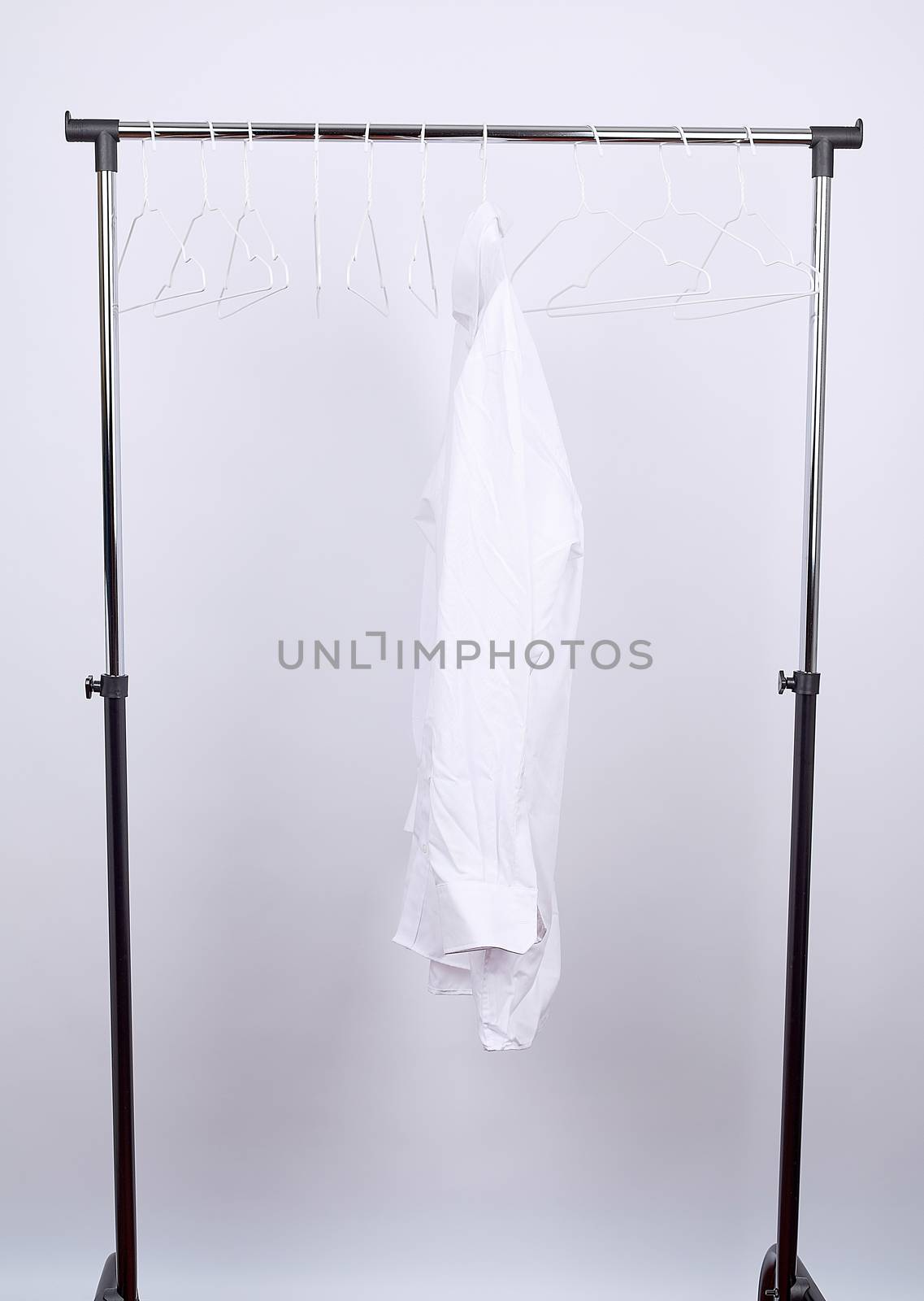 white men's crumpled shirt hanging on a metal hanger, white background, concept of loneliness