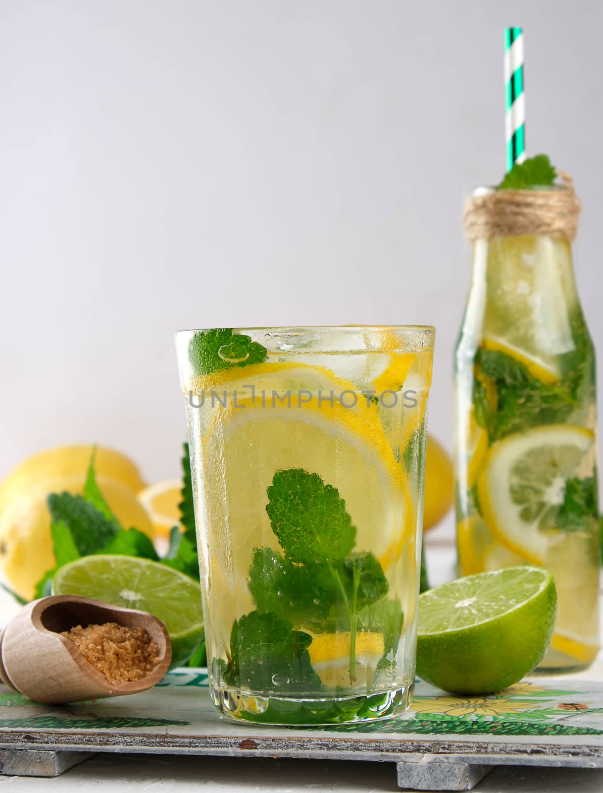 summer refreshing drink lemonade with lemons, mint leaves, lime in a glass, next to the ingredients for making a cocktail