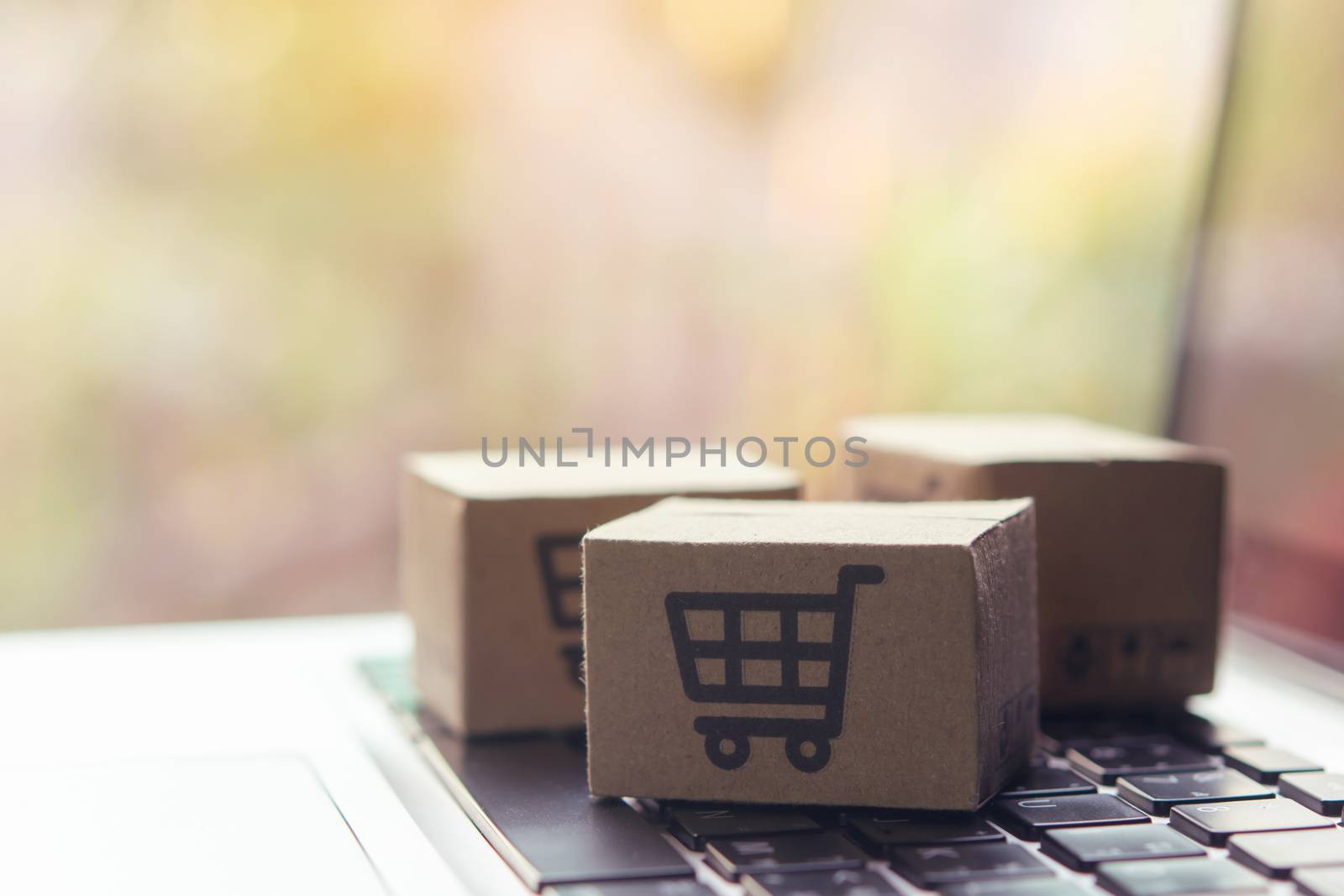 Online shopping - Paper cartons or parcel with a shopping cart logo on a laptop keyboard. Shopping service on The online web and offers home delivery.
