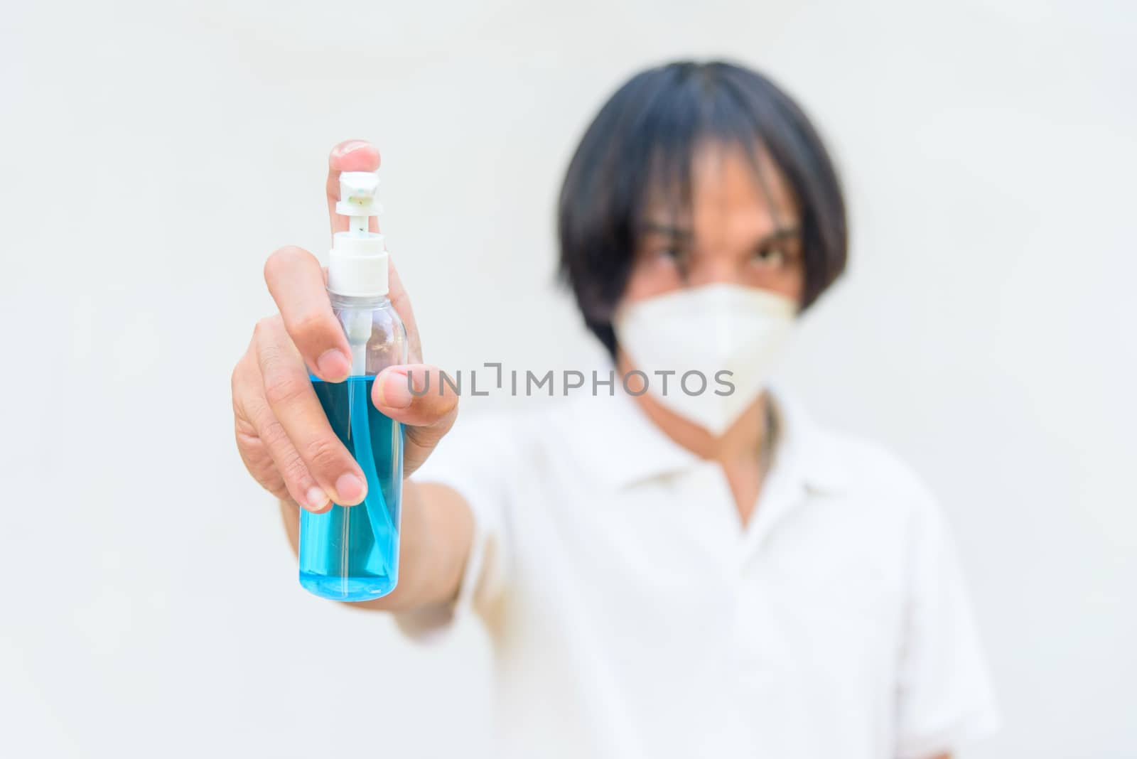 A asian man wear mask and spray the alcohol gel for cleaning disease