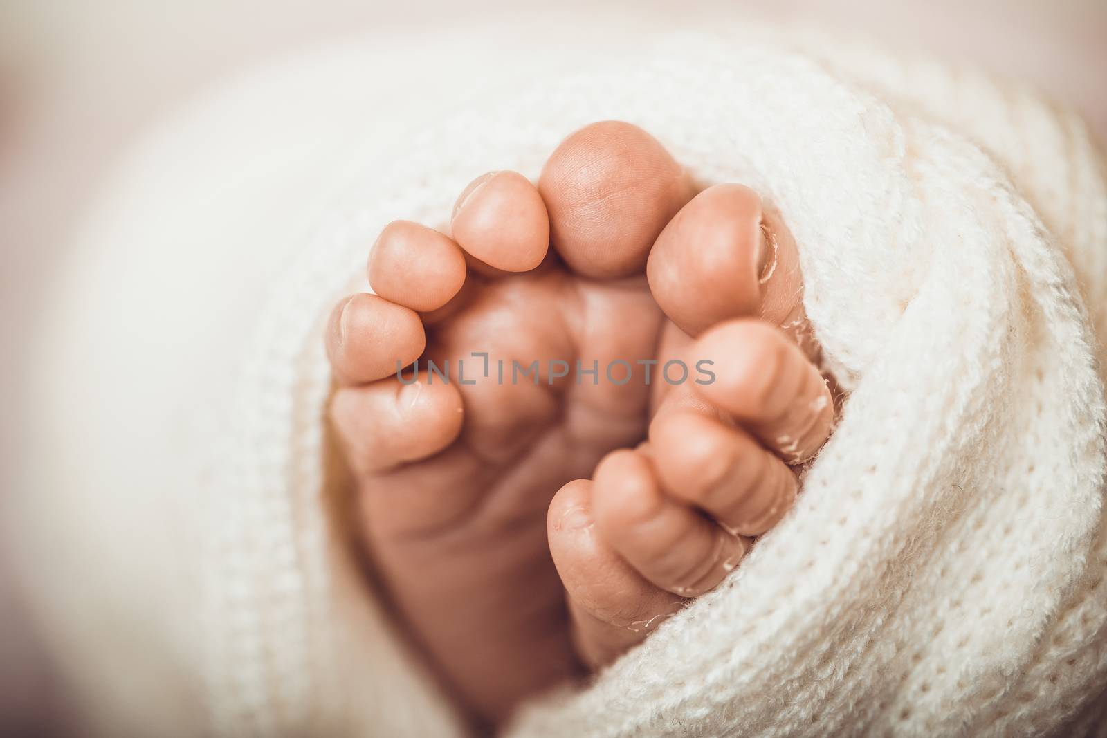 Tiny foot of newborn baby. Soft newborn baby feet against a pink blanket. Baby girl feet with toes curled up. by boskorelly