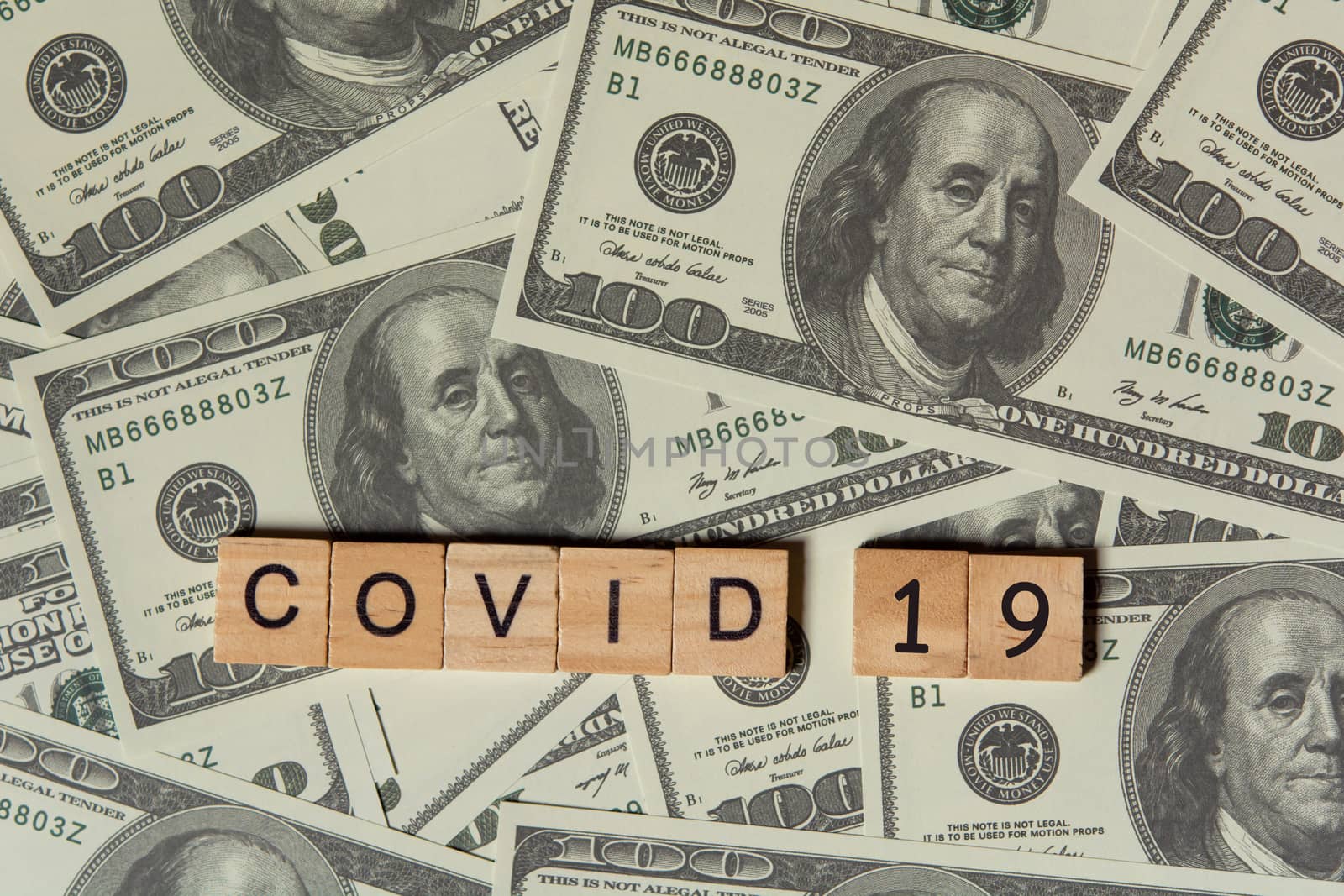 COVID-19 coronavirus with wooden alphabet blocks, on 100 dollar money background with copy space
