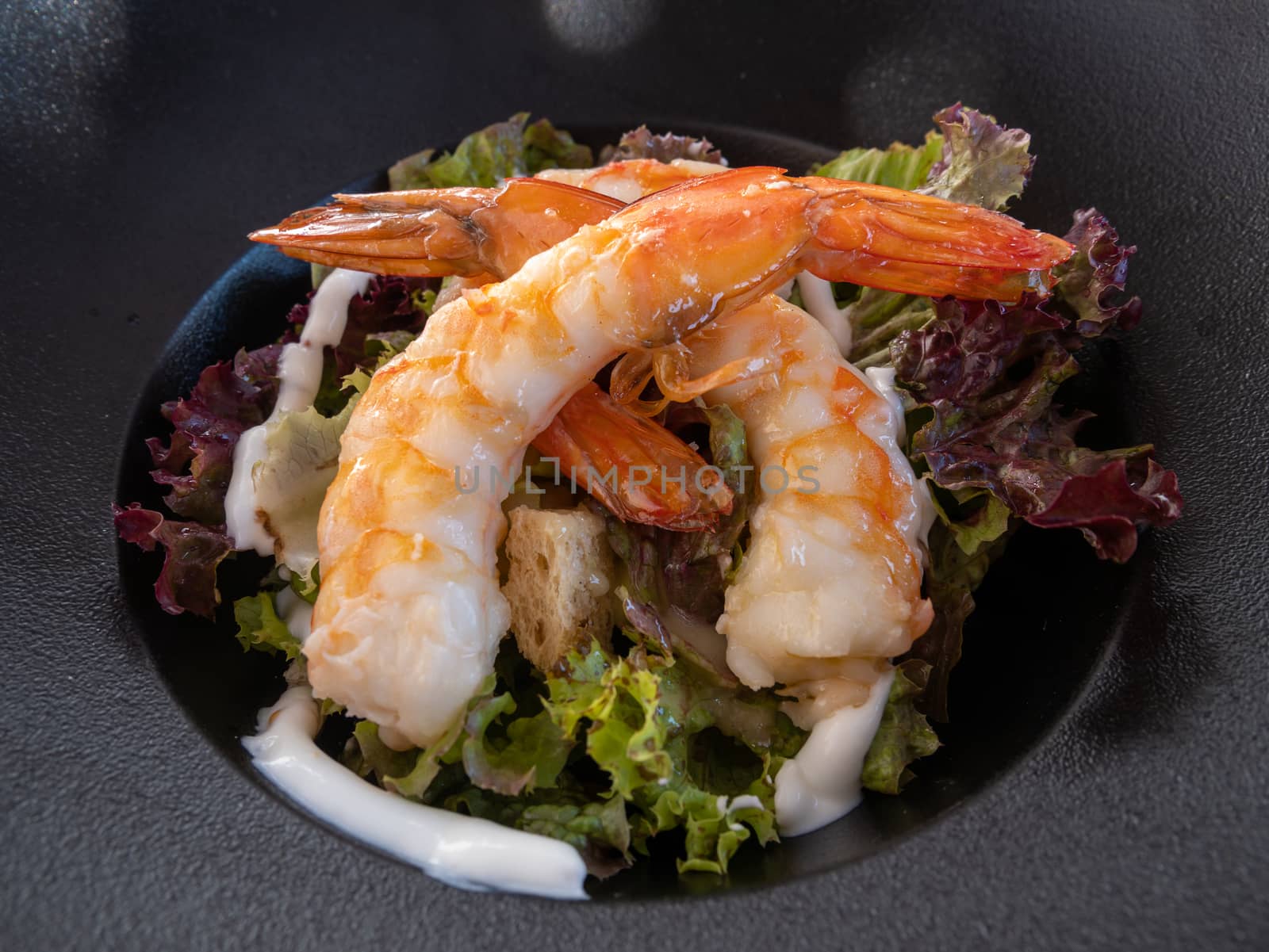 Shrimp caesar salad in white plate, Mediterranean cuisine.