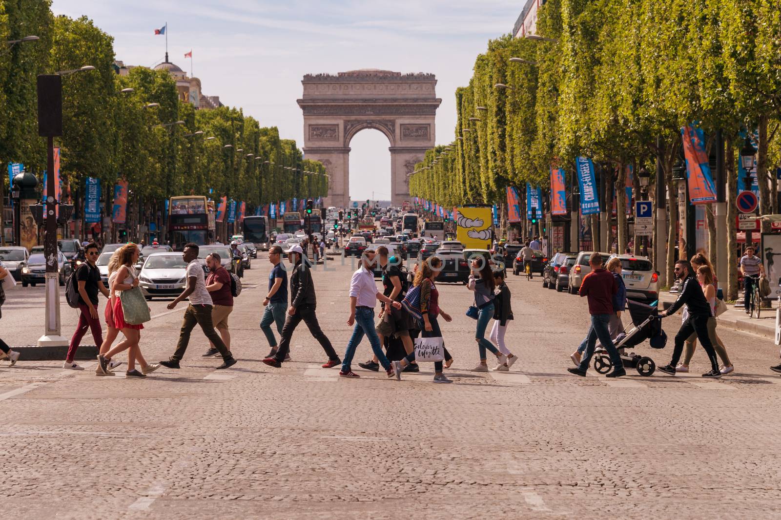 Paris, France - 23 June 2018: A crowd of people crossing Avenue des Champs-Elysees with Arc de Triomphe in the Background