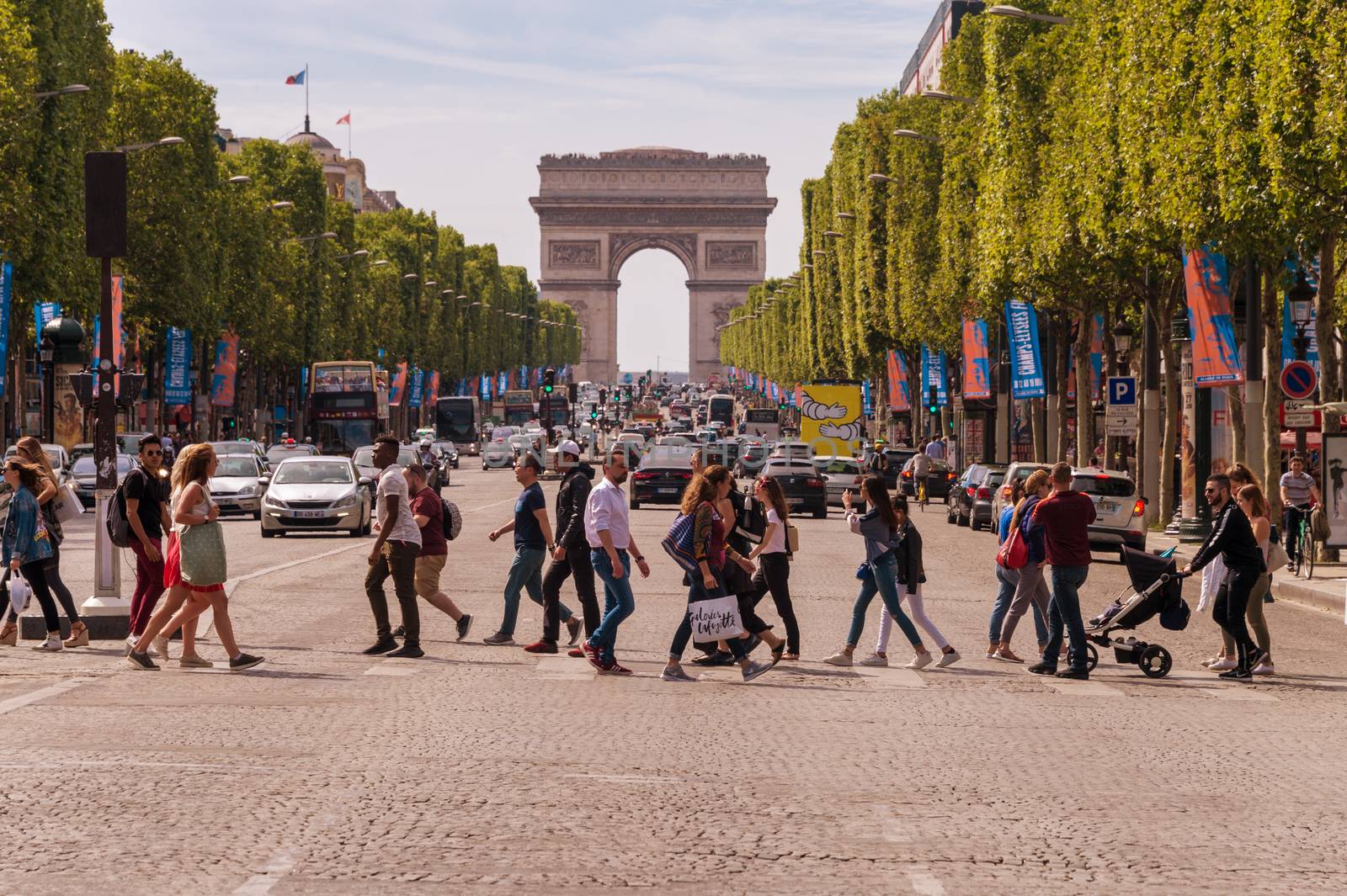 Paris, France - 23 June 2018: A crowd of people crossing Avenue des Champs-Elysees with Arc de Triomphe in the Background