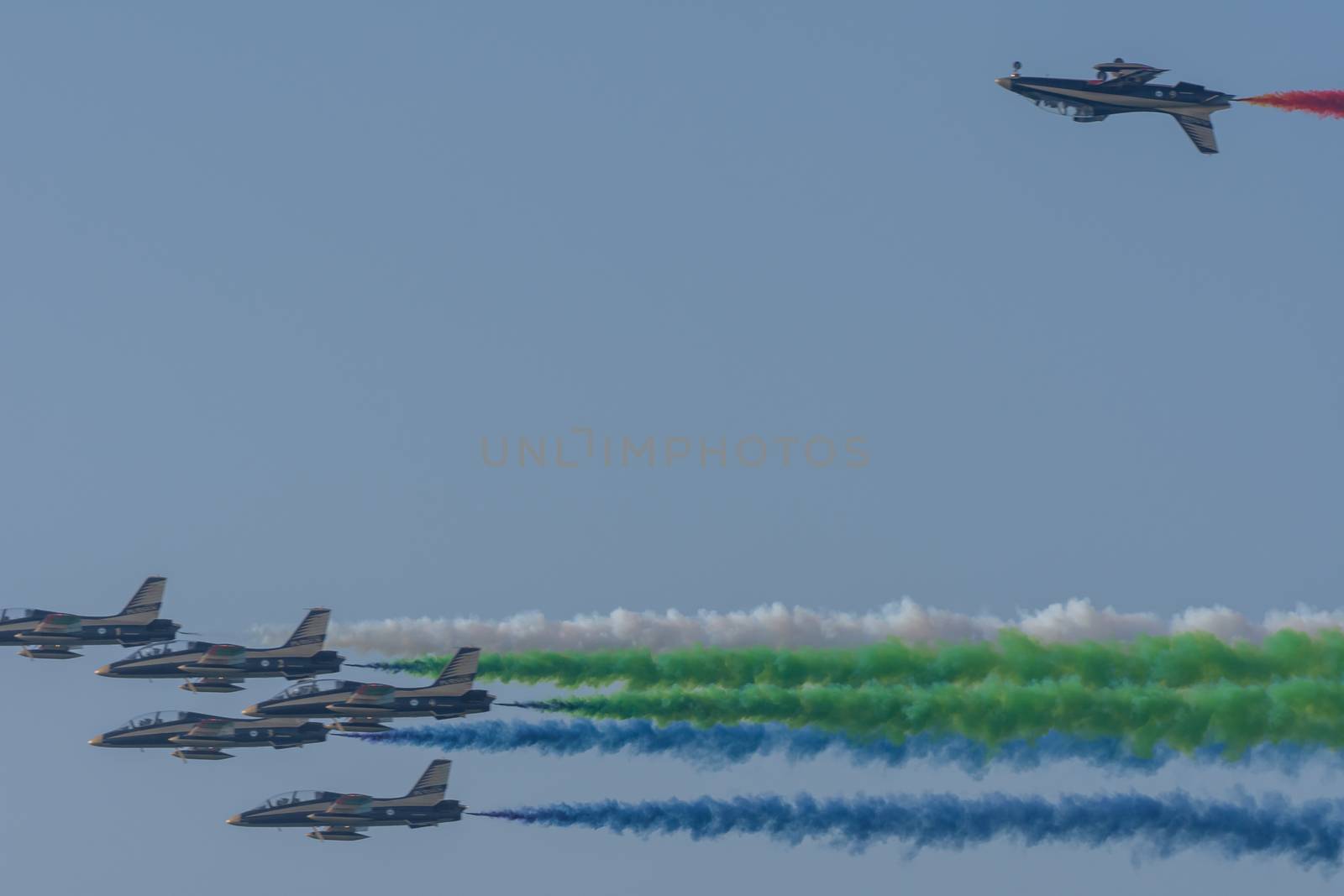 UAE Largest Military Union Fortress 7 Show in Umm al Quwain with coordinated military aircrafts showing the UAE flag colors on the bright blue sky