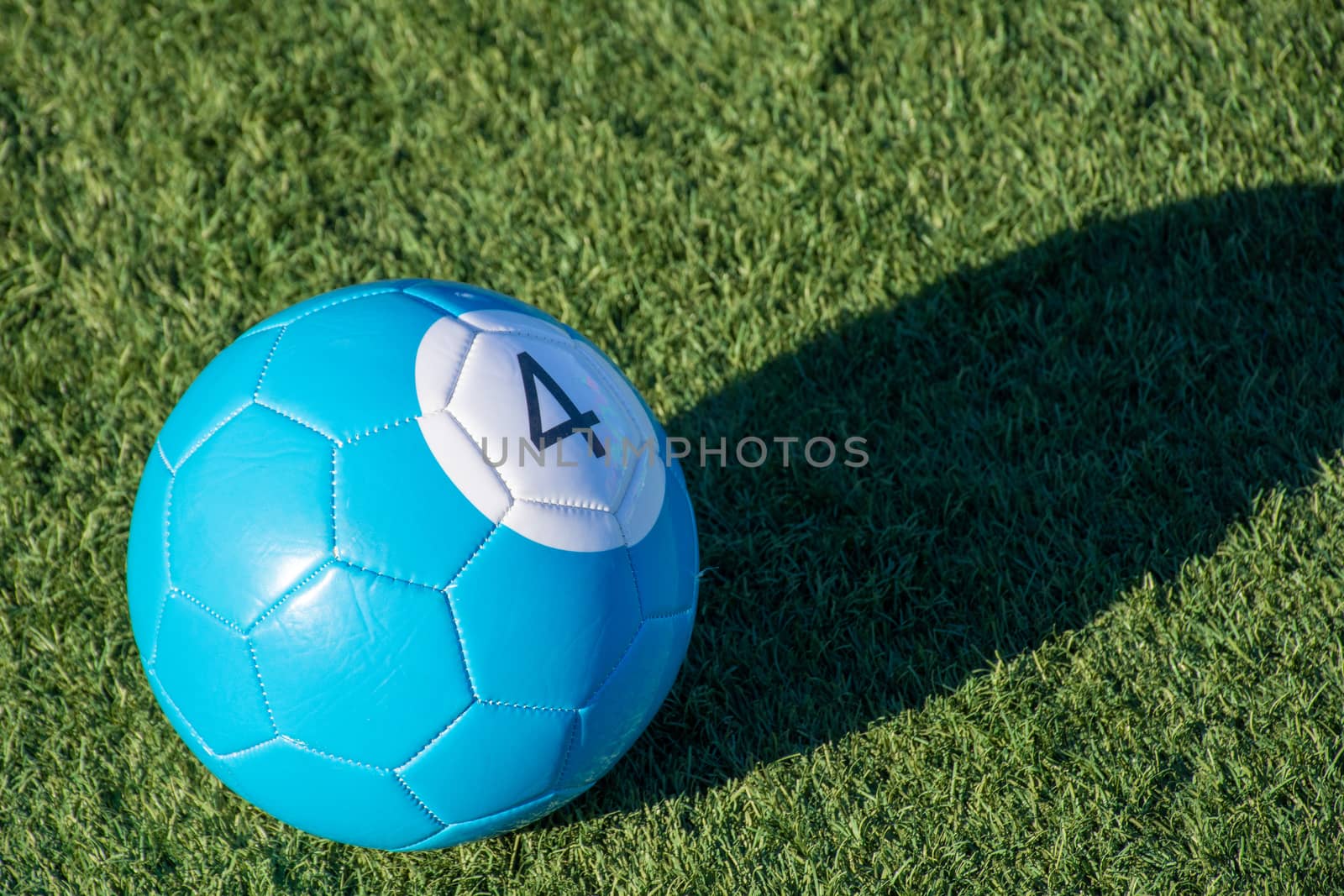 Blue number 4 soccer billiards or pool ball on green grass with  by kingmaphotos