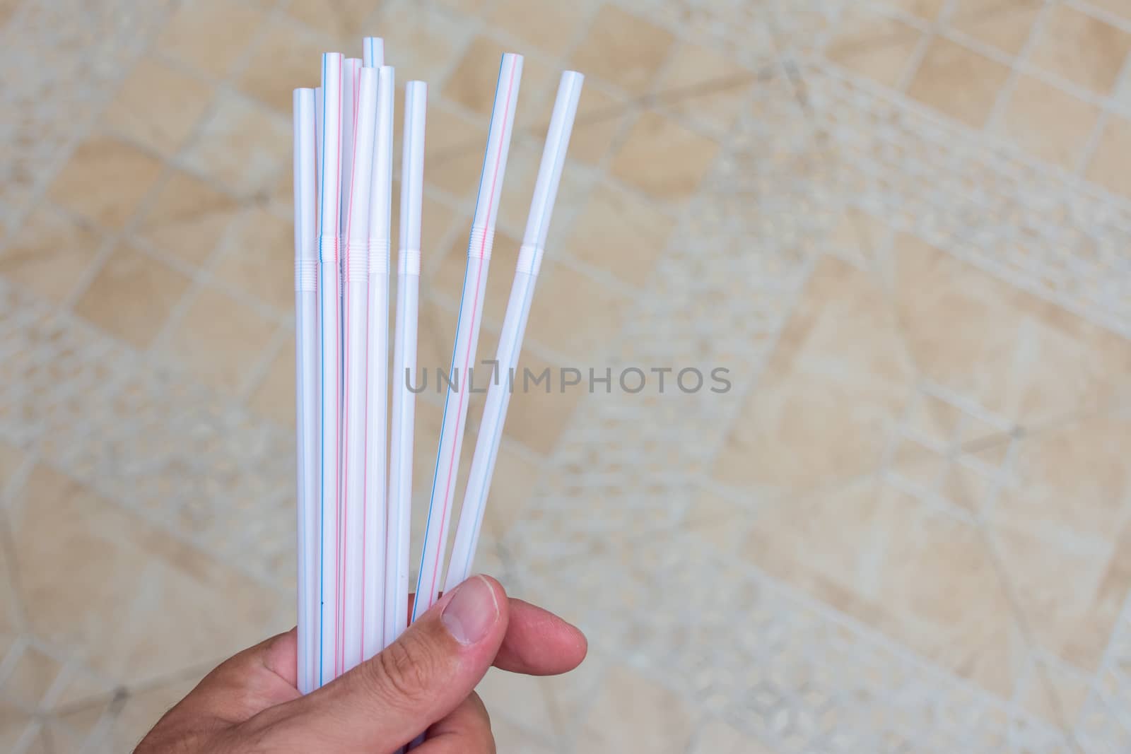 Hand holding household plastic straws symbolizing plastic pollution global problems and need for environmental change.
