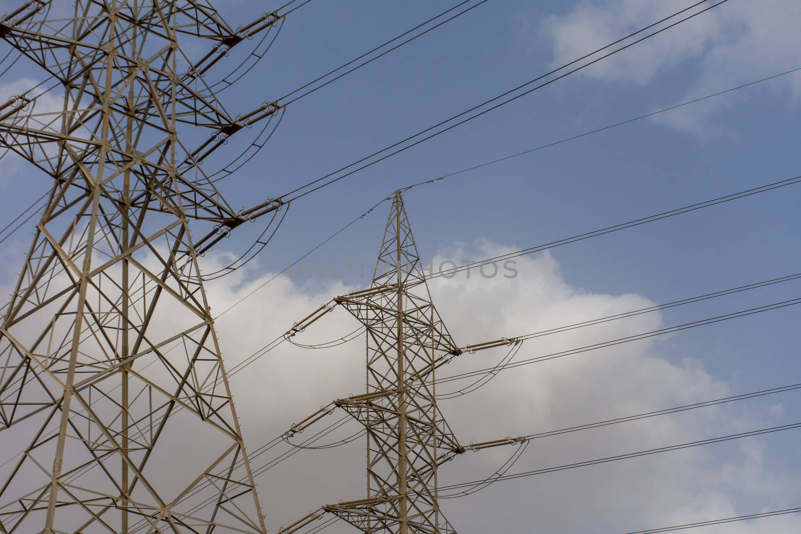 High voltage powerlines on blue sky and cloudy background in the by kingmaphotos