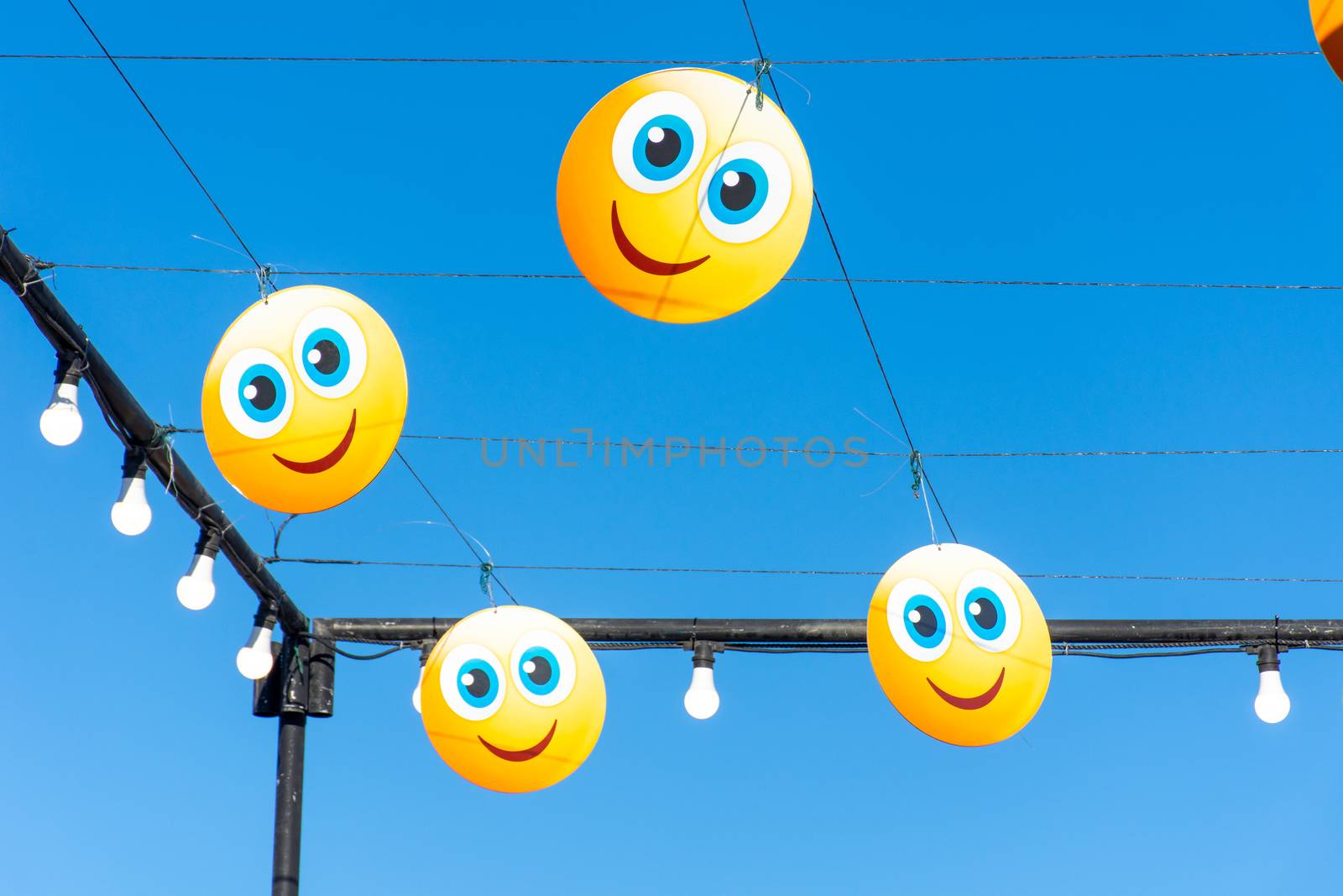 Hanging happy emojis or emoticons on blue sky for a street festival. Happiness, valentine's day, and joy concpets.
