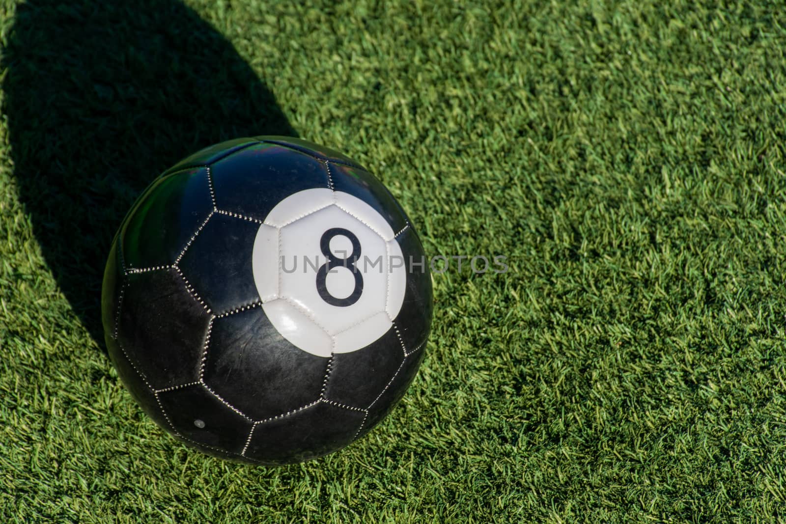 Black Eight (8) ball a soccer billiards or pool ball on green gr by kingmaphotos