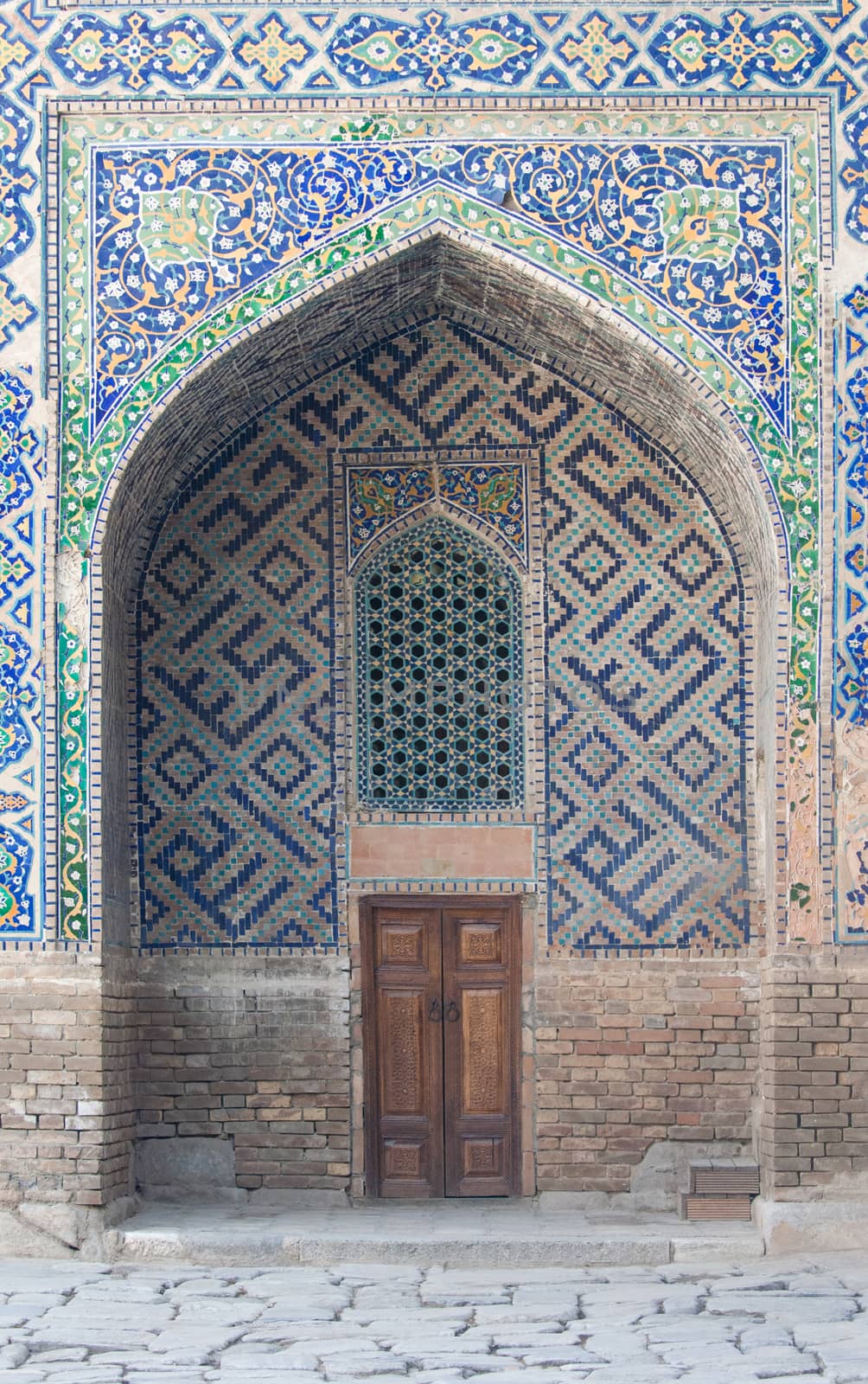 A wooden door in the archway with ancient Asian ornament. the details of the architecture of medieval Central Asia