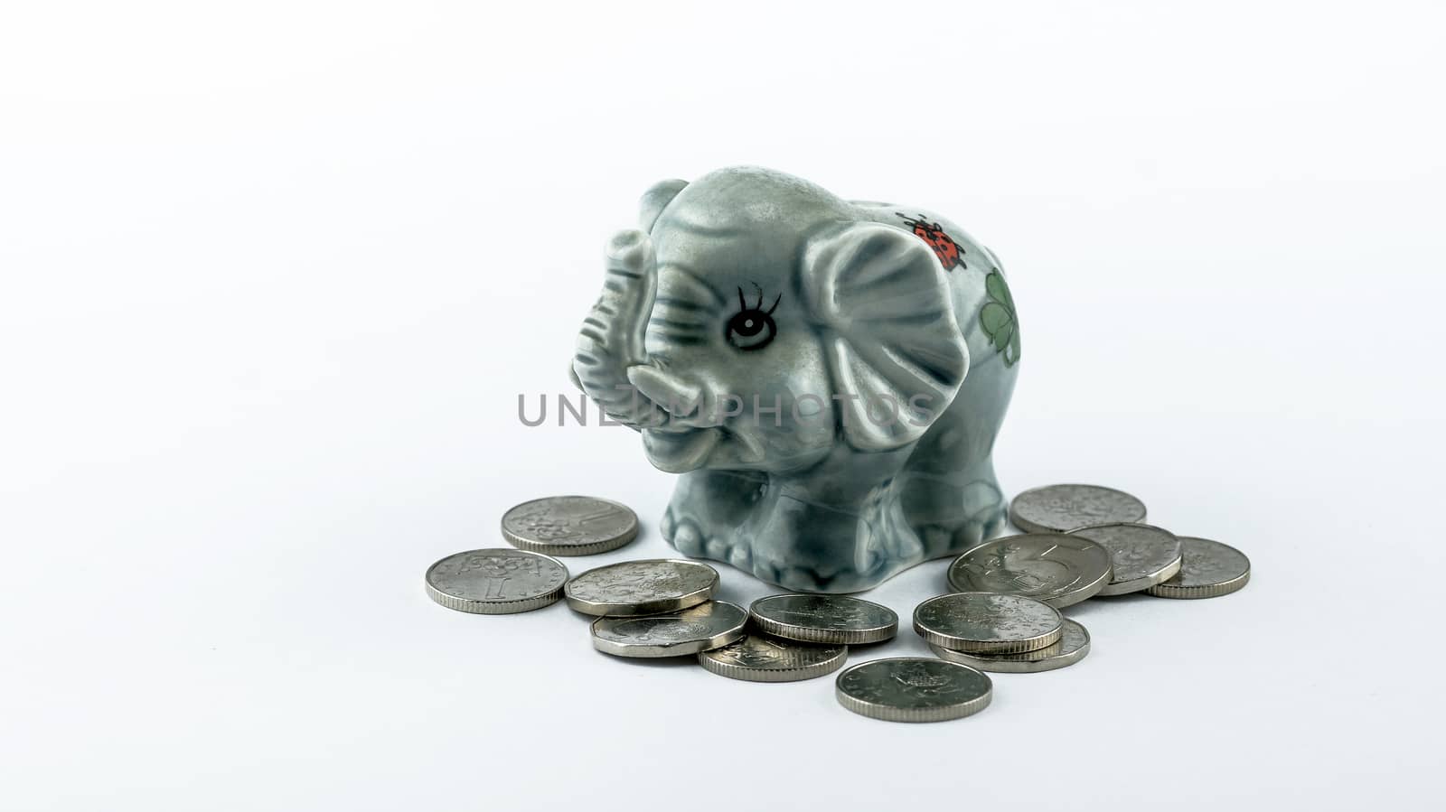 Moneybox of an elephant with Czech coins around isolated on a white background.